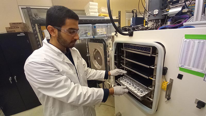 Researcher loading a tray of vials into a freeze dryer