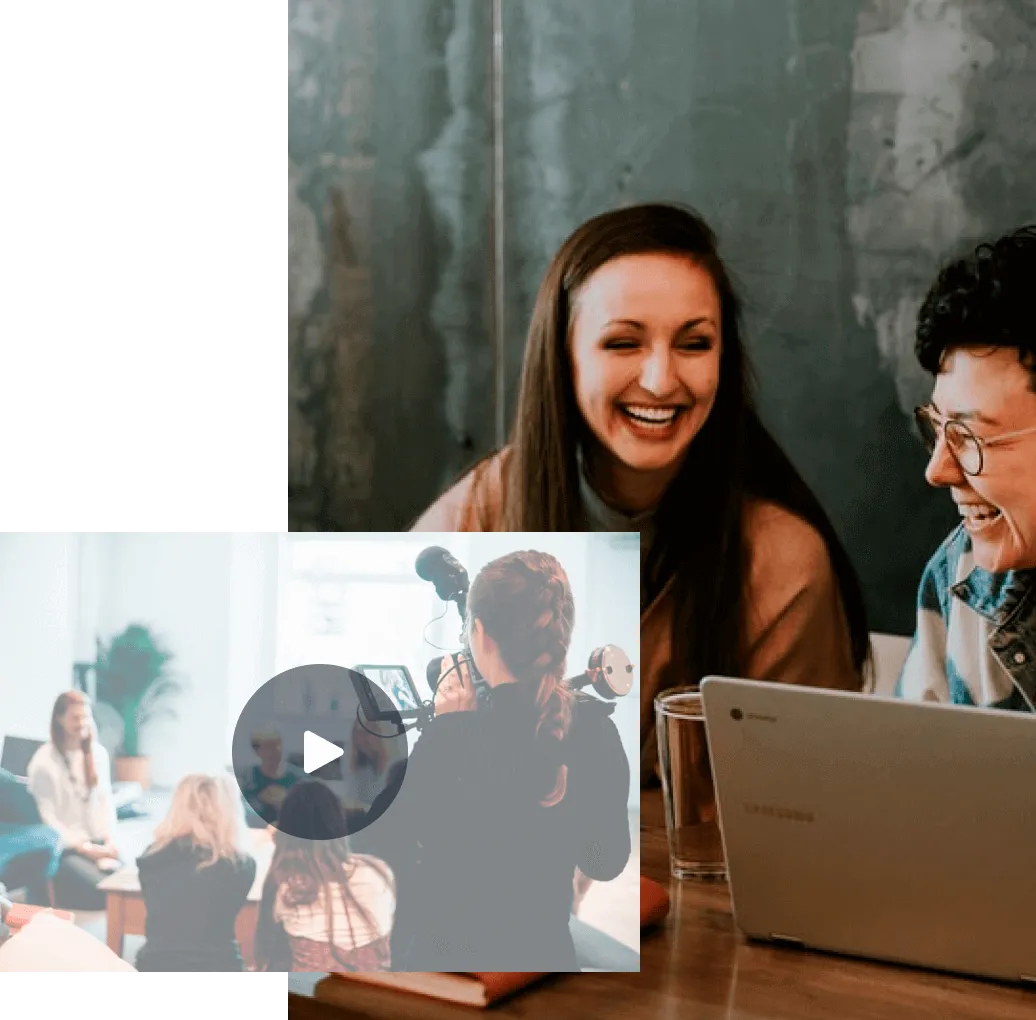 Two people smiling and working together at a table with a laptop and glass of water.