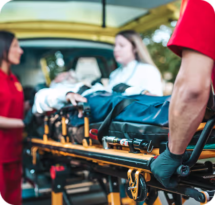 Medical professionals loading a patient on a stretcher into an ambulance.