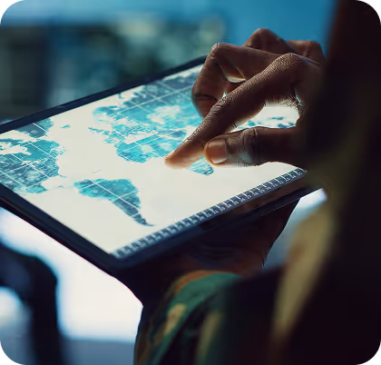 Person's hand pointing at a digital world map displayed on a tablet screen.