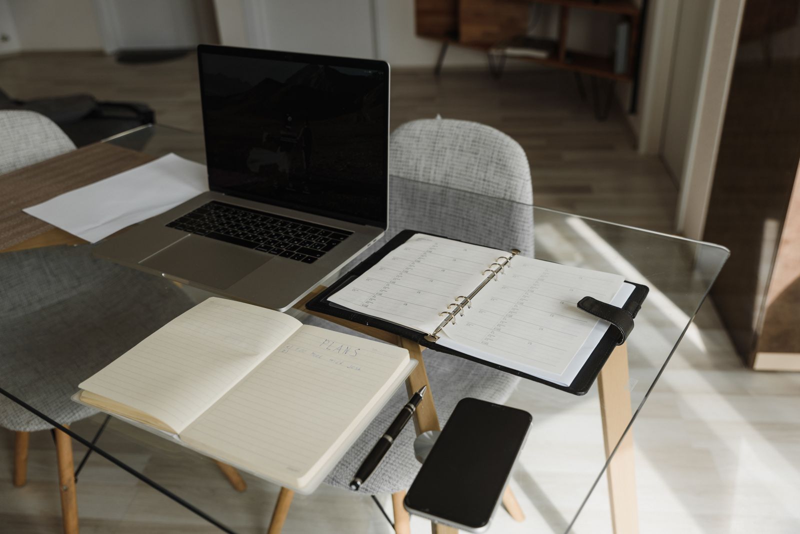 Laptop, notebook, and planning materials arranged on an office desk