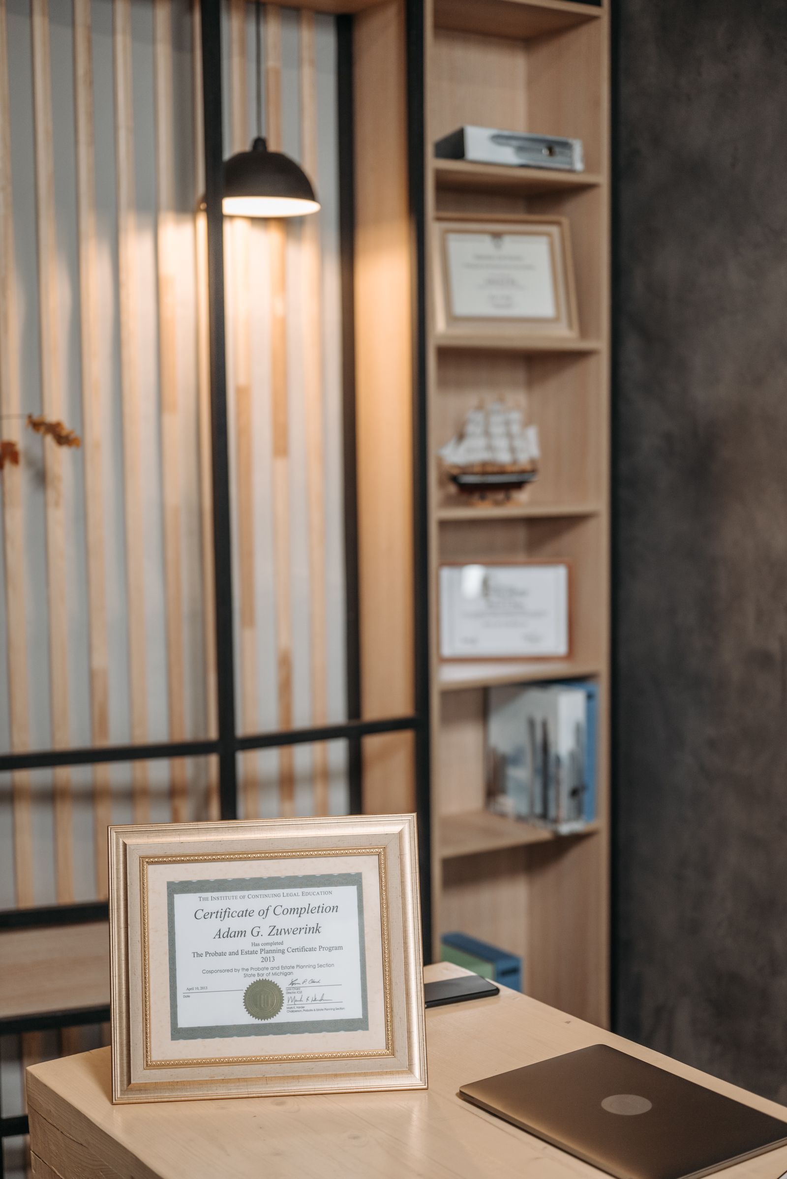 Framed certificate on a desk in a warm, book-lined office