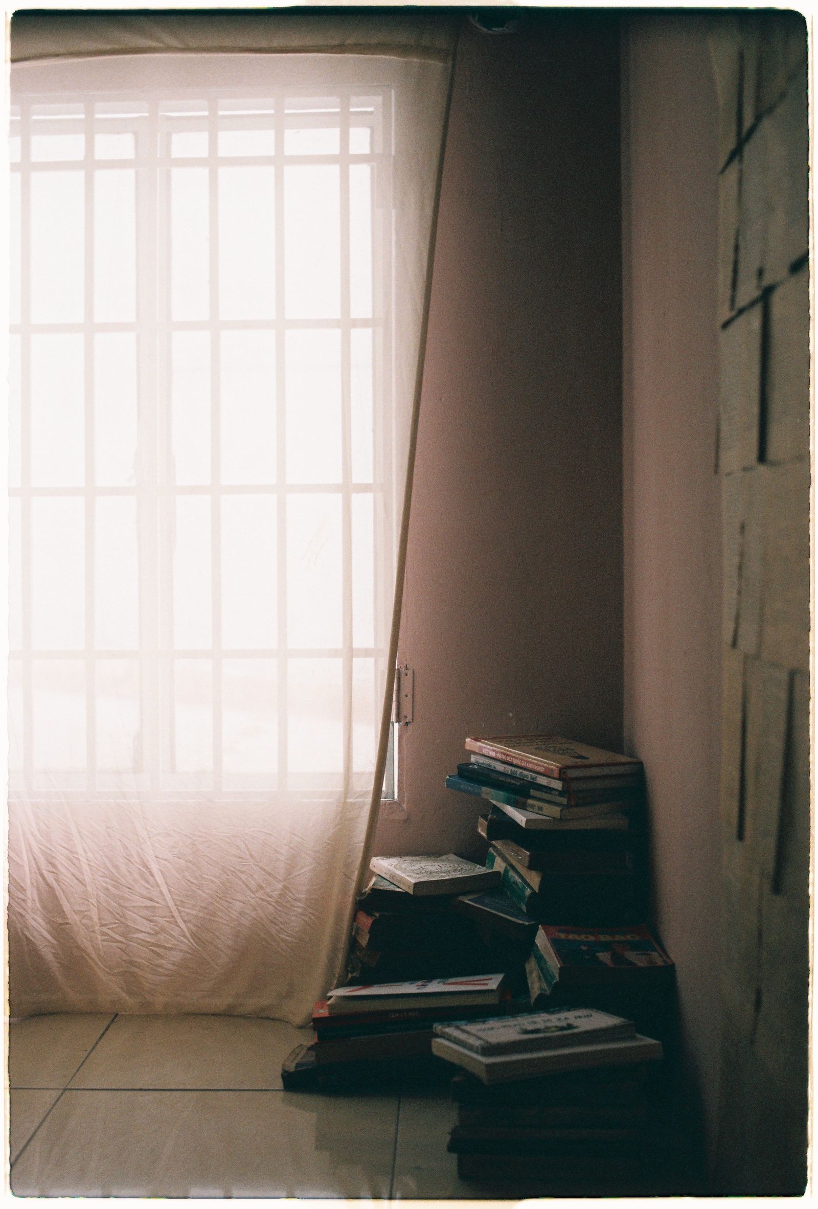 Books stacked by a window curtain