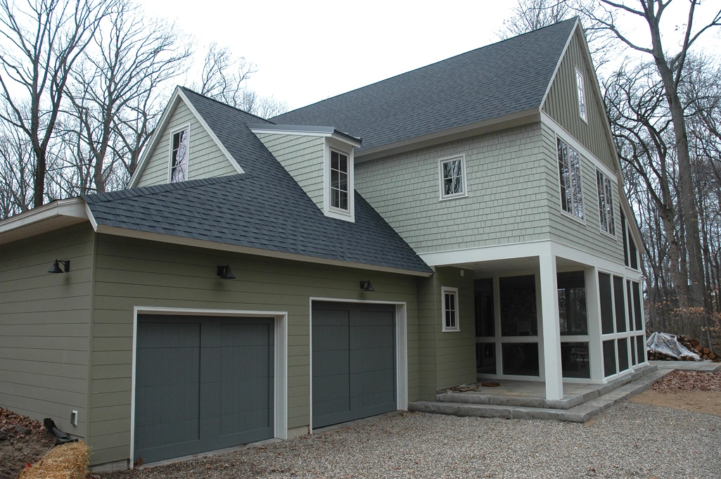 CAMP house with pale green siding, two garage doors, and a covered porch