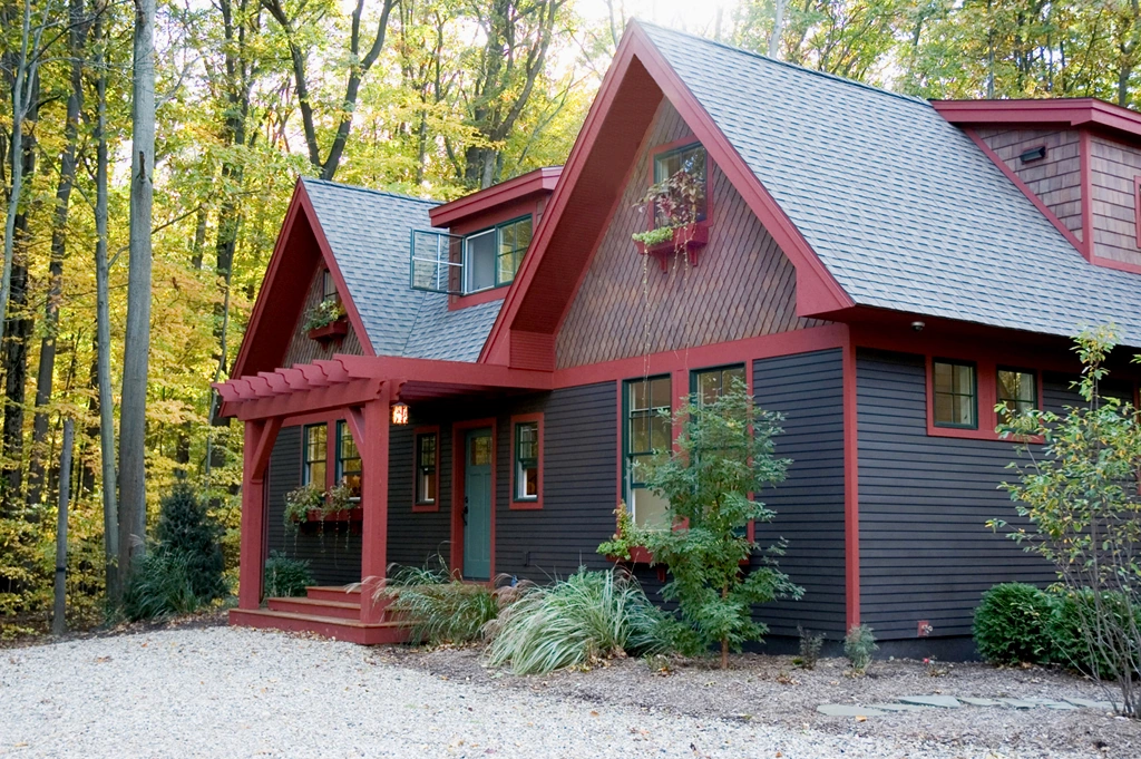 Christopher's Cottage with dark siding, red trim, steep gables, and a small front porch