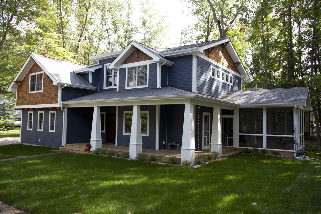 The Willow, finished: front corner with blue siding, shingled gables and a deep front porch