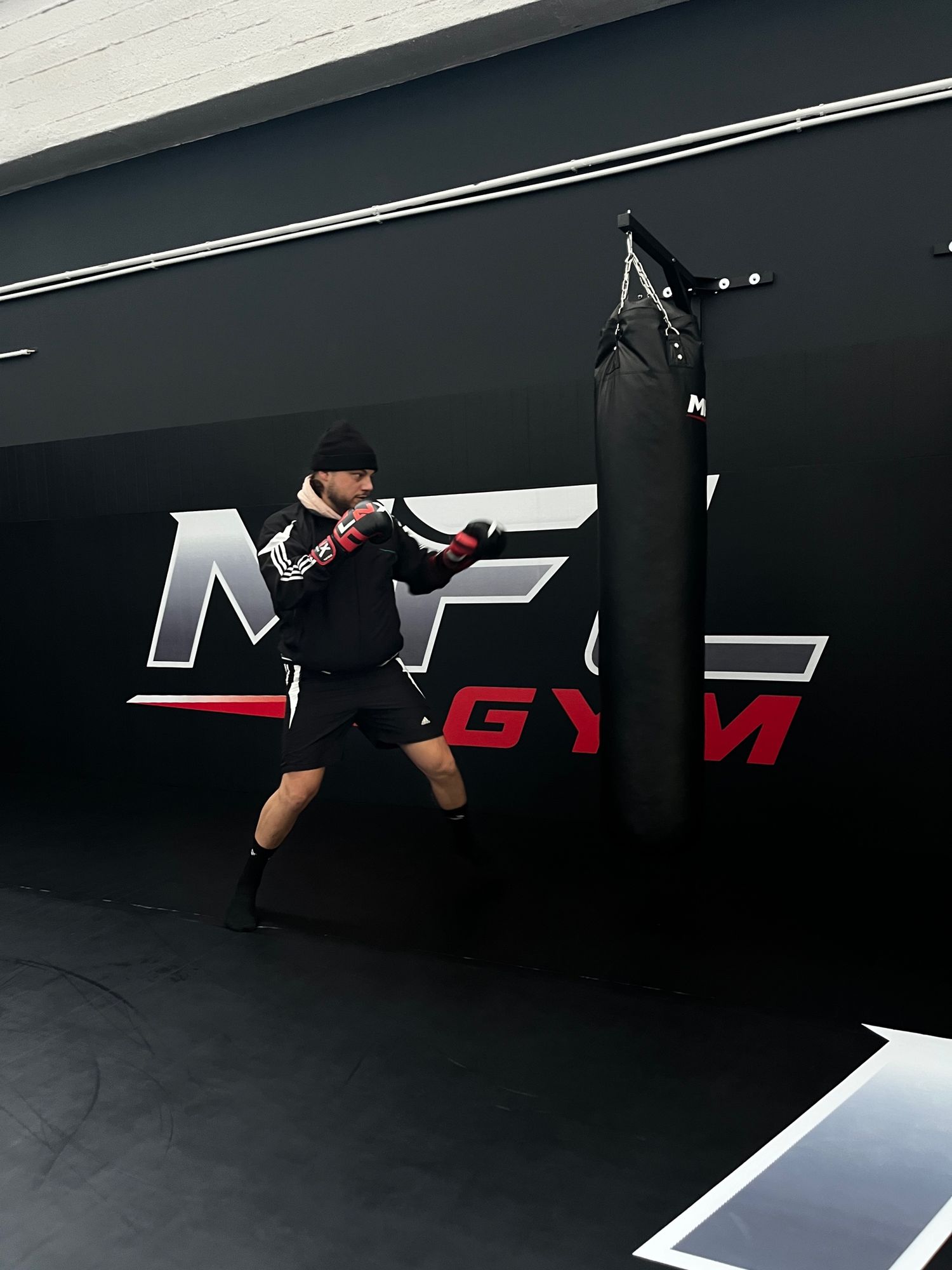 Boxtraining am Sandsack vor dem MFL-GYM-Logo