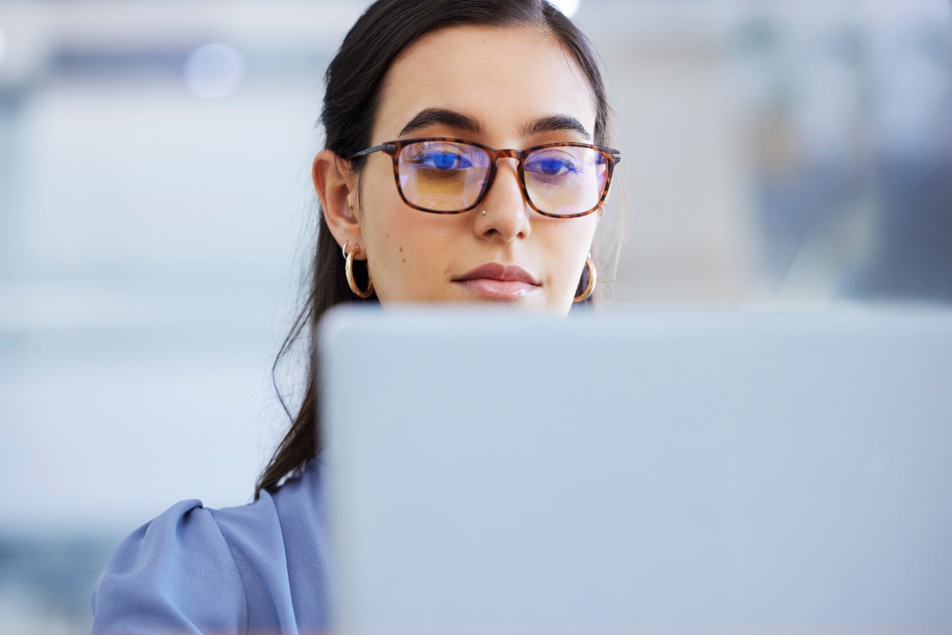 Close-up van vrouw met bril die naar een laptopscherm kijkt