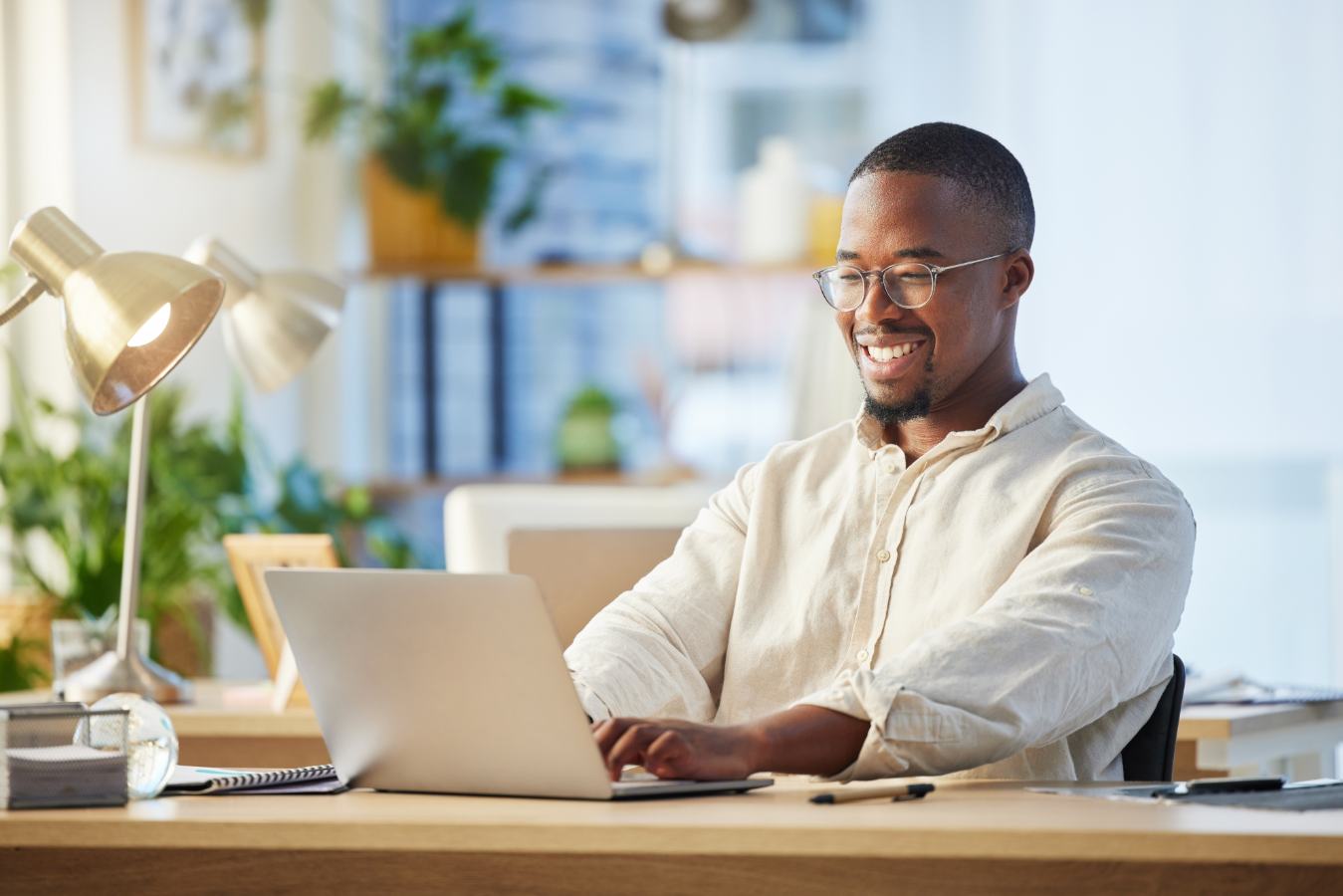 Lachende man typt op laptop aan houten bureau met bureaulampen