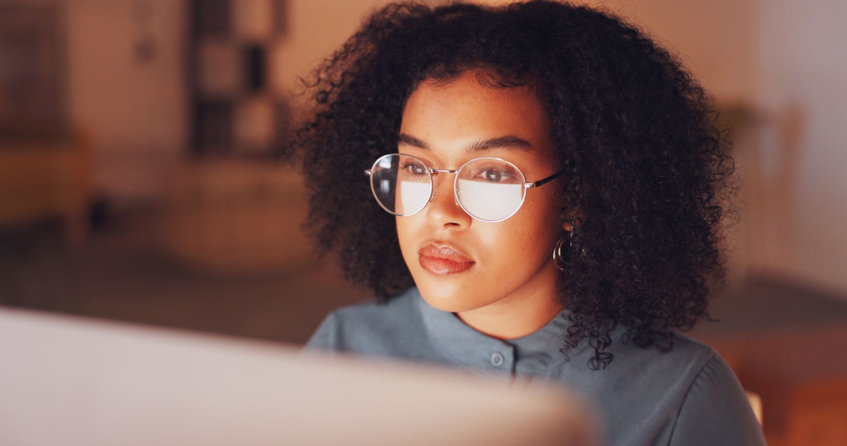 Close-up van vrouw met bril en krullend haar achter computerscherm