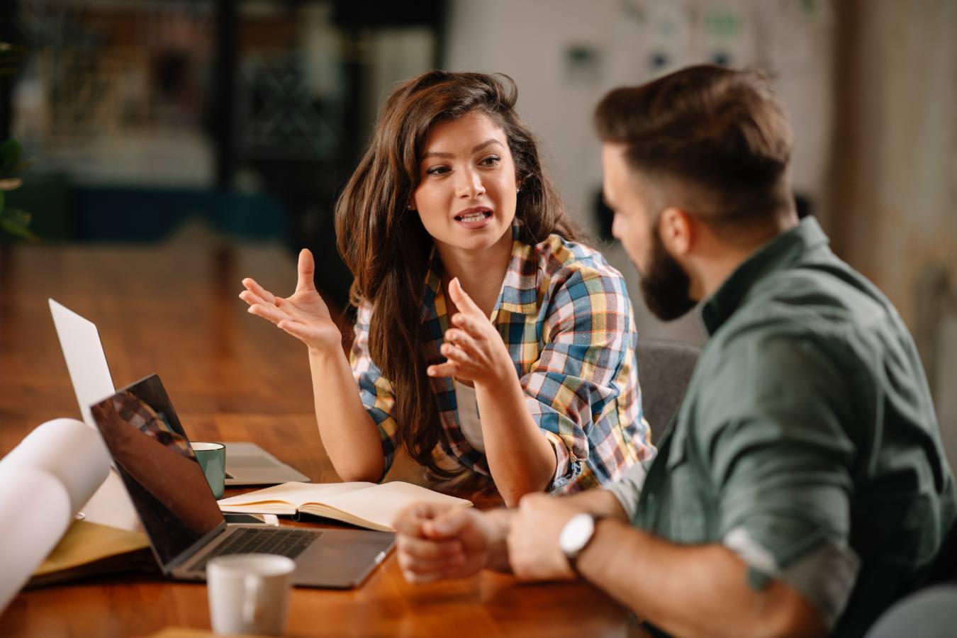 Vrouw legt iets uit aan collega met notitieboek en laptops
