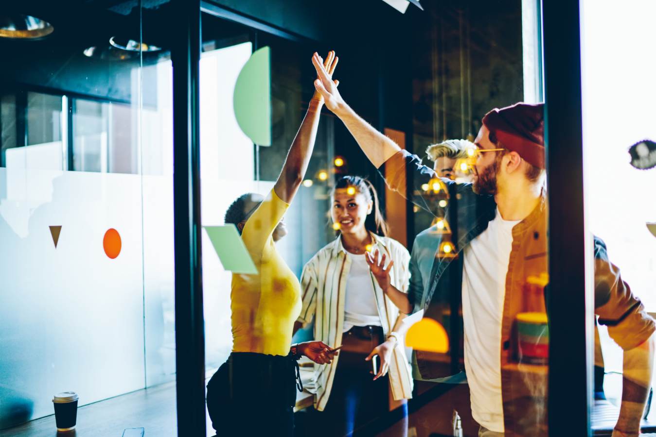 Collega's geven high five achter een glazen kantoorwand
