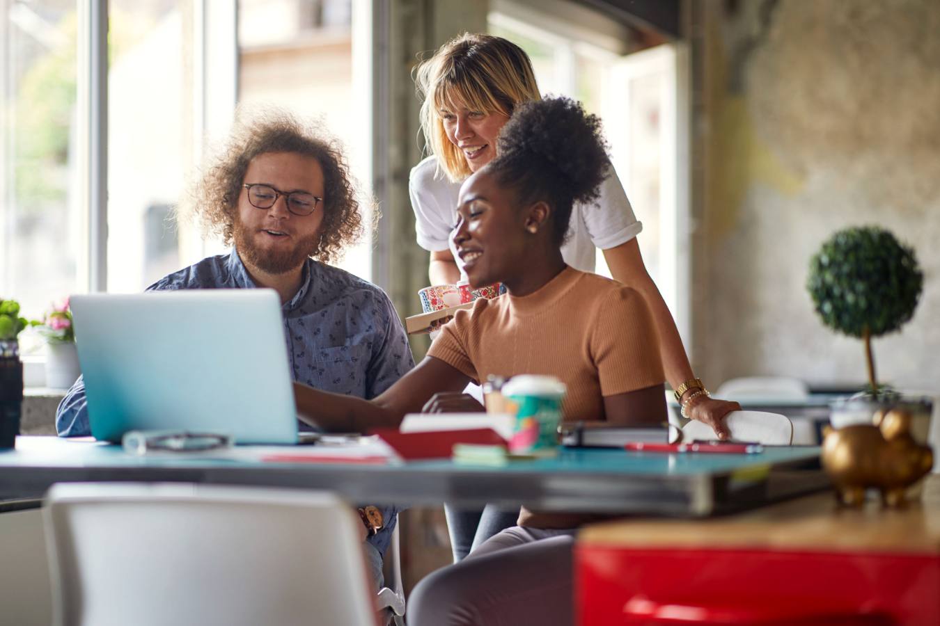 Drie collega's kijken samen lachend naar een laptopscherm