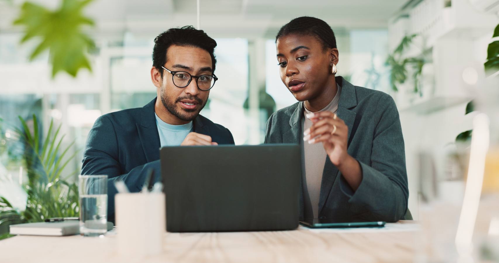 Man en vrouw in pak bespreken iets achter een laptop