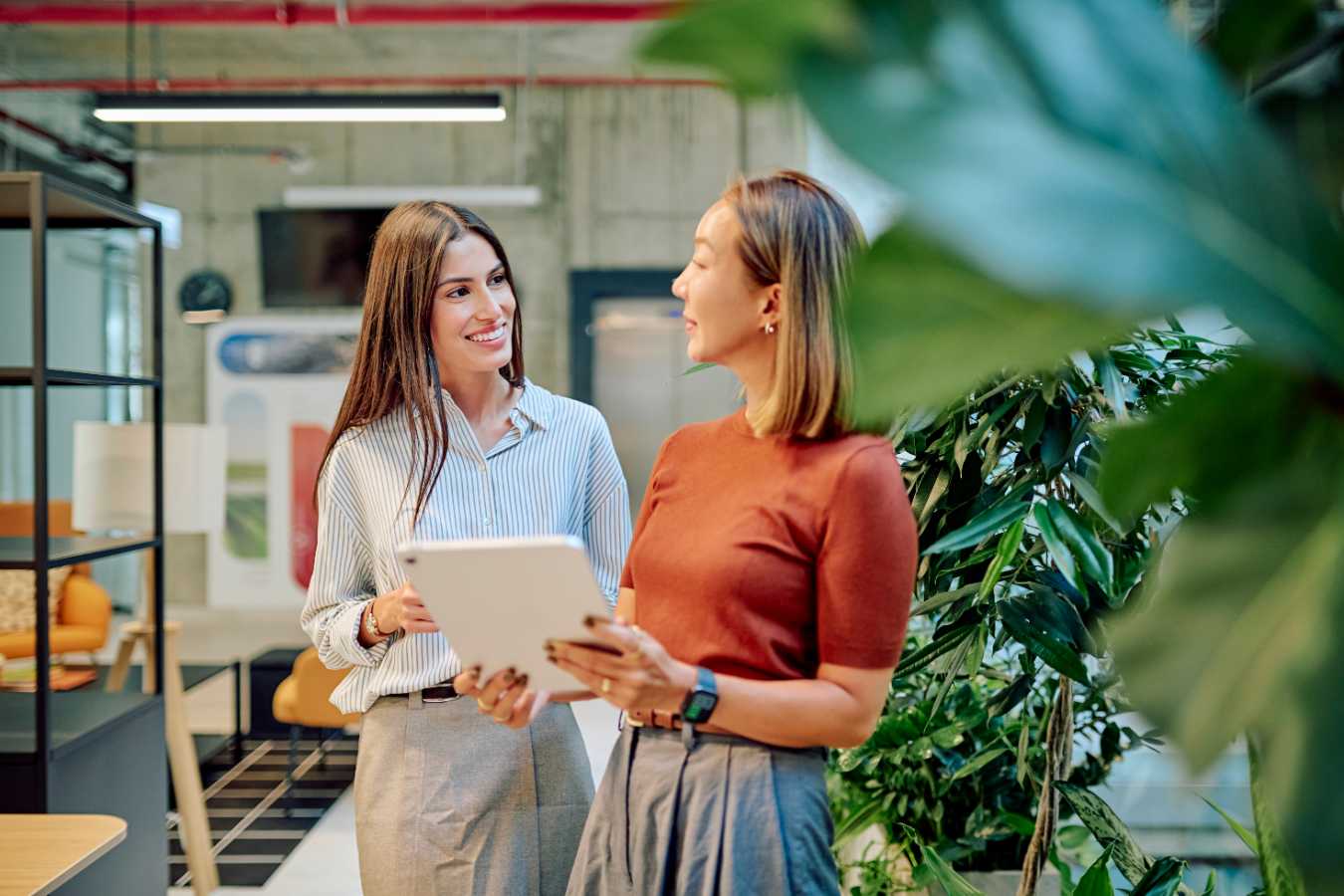 Two women talking while holding a tablet