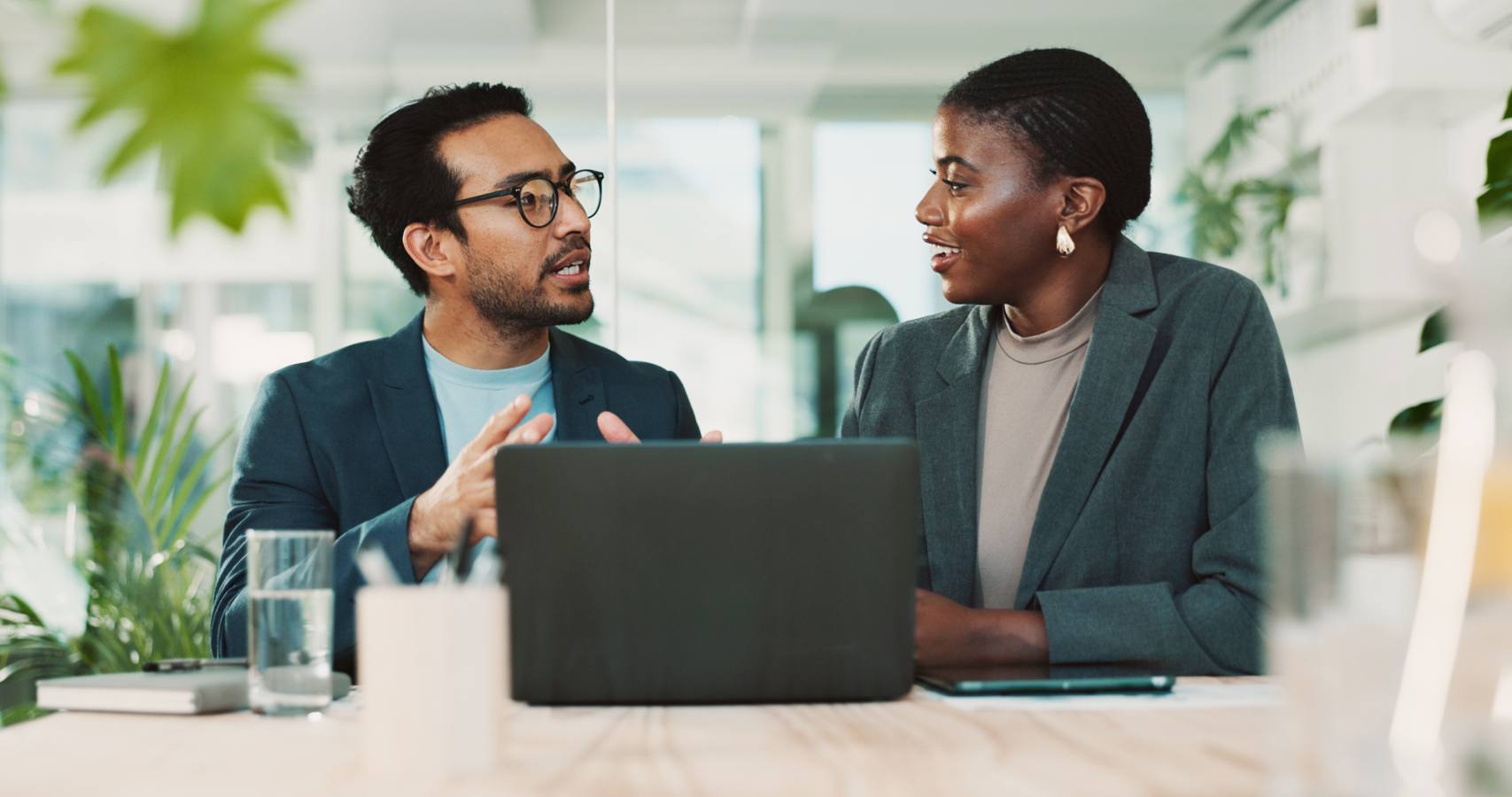 Business duo in conversation behind a laptop in an office