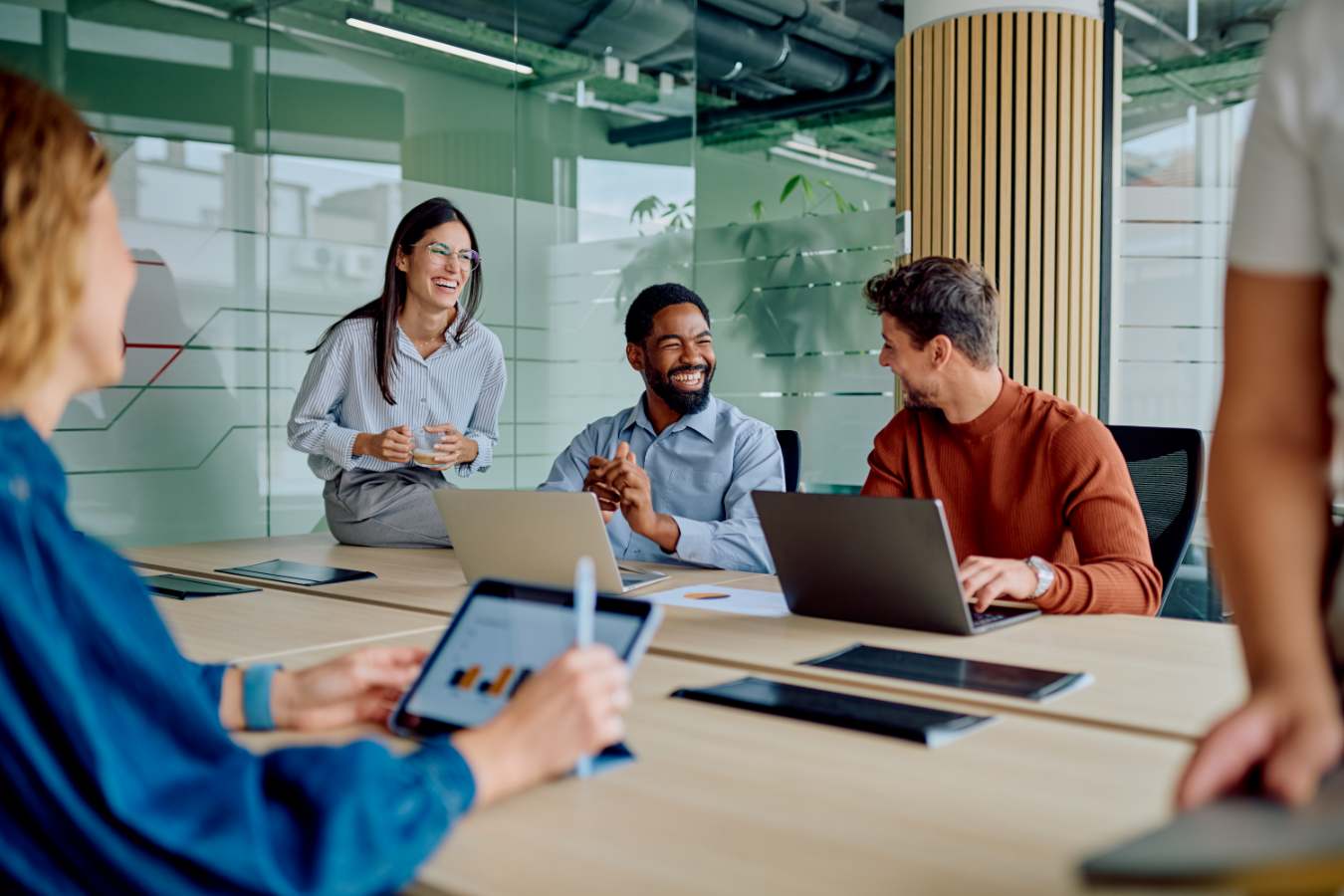Groep collega's overlegt aan tafel met laptops en tablet