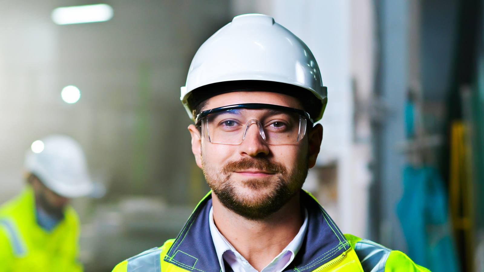 Portret van man met witte helm en veiligheidsbril in fabriek