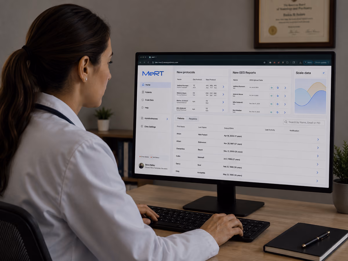 A female doctor in a white coat is sitting at a desk, working on a computer displaying MeRT software with patient data, new protocols, EEG reports, and scale data on the screen.