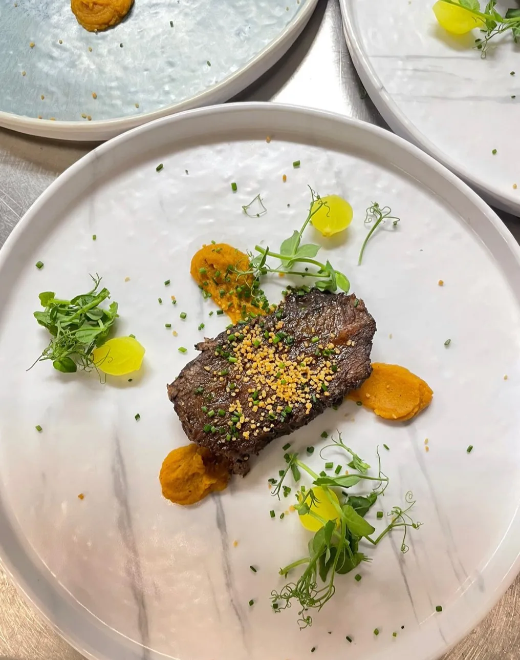 Vleesgerecht met groenten en kruiden op een wit bord