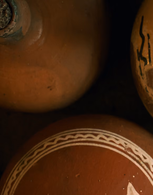 Close-up view of three brown ceramic pots, one with white decorative patterns on its surface, placed against a dark background.