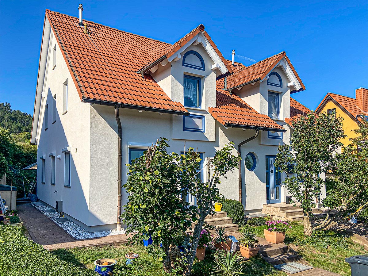 Frisch gestrichene weiße Fassade eines Doppelhauses mit roten Dachziegeln