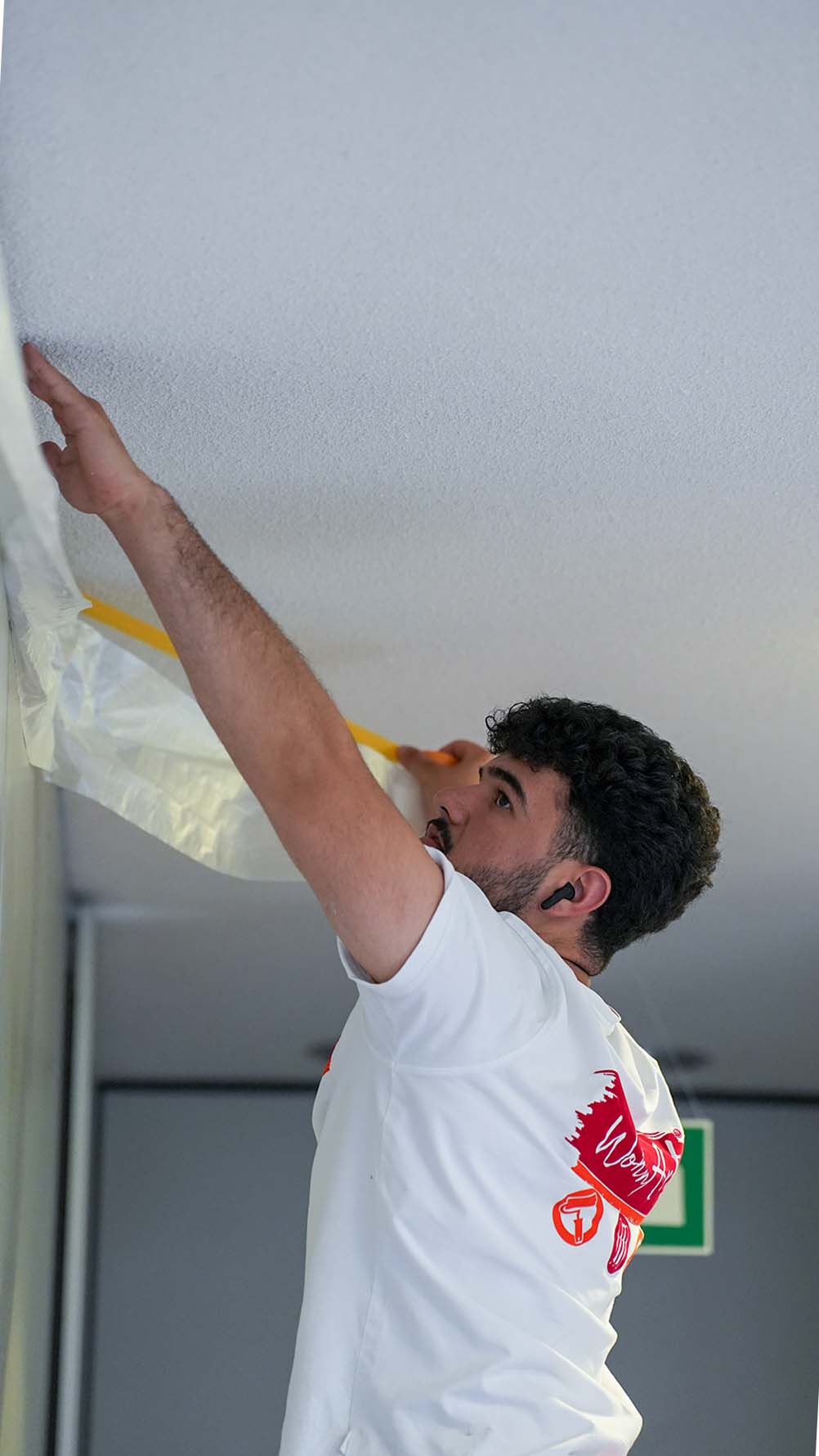 WohnArt Maler klebt eine Decke vor dem Anstrich sauber ab