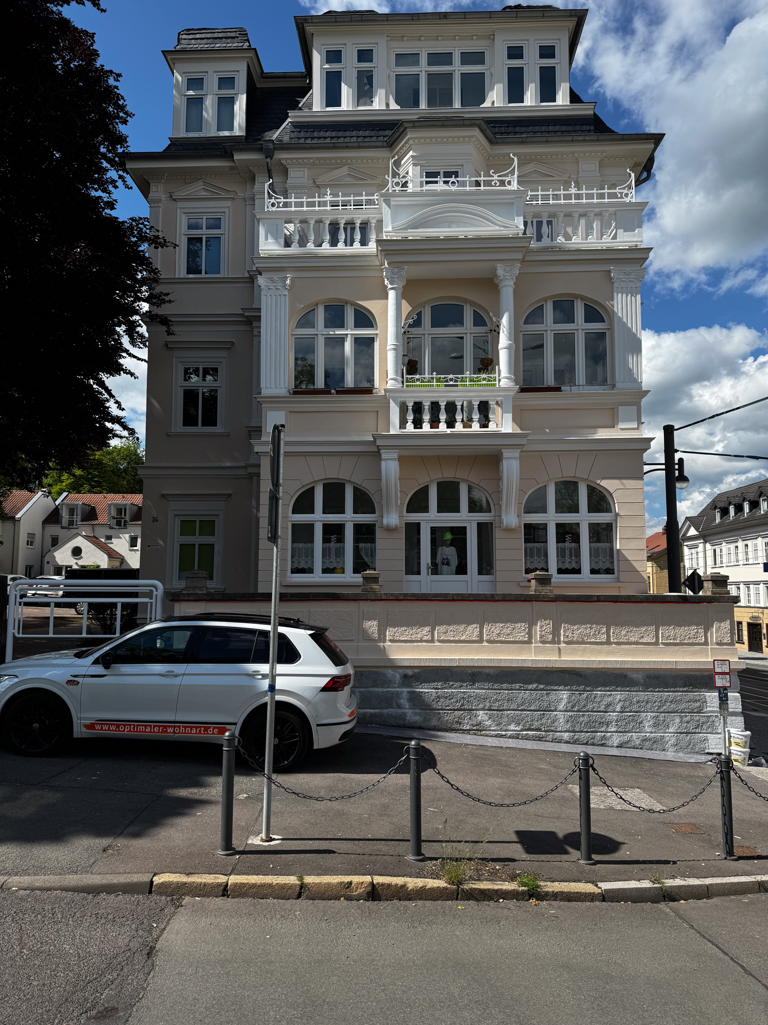 Gebäudefront mit grau-weiß gestrichener Fassade und Rundbogenportalen