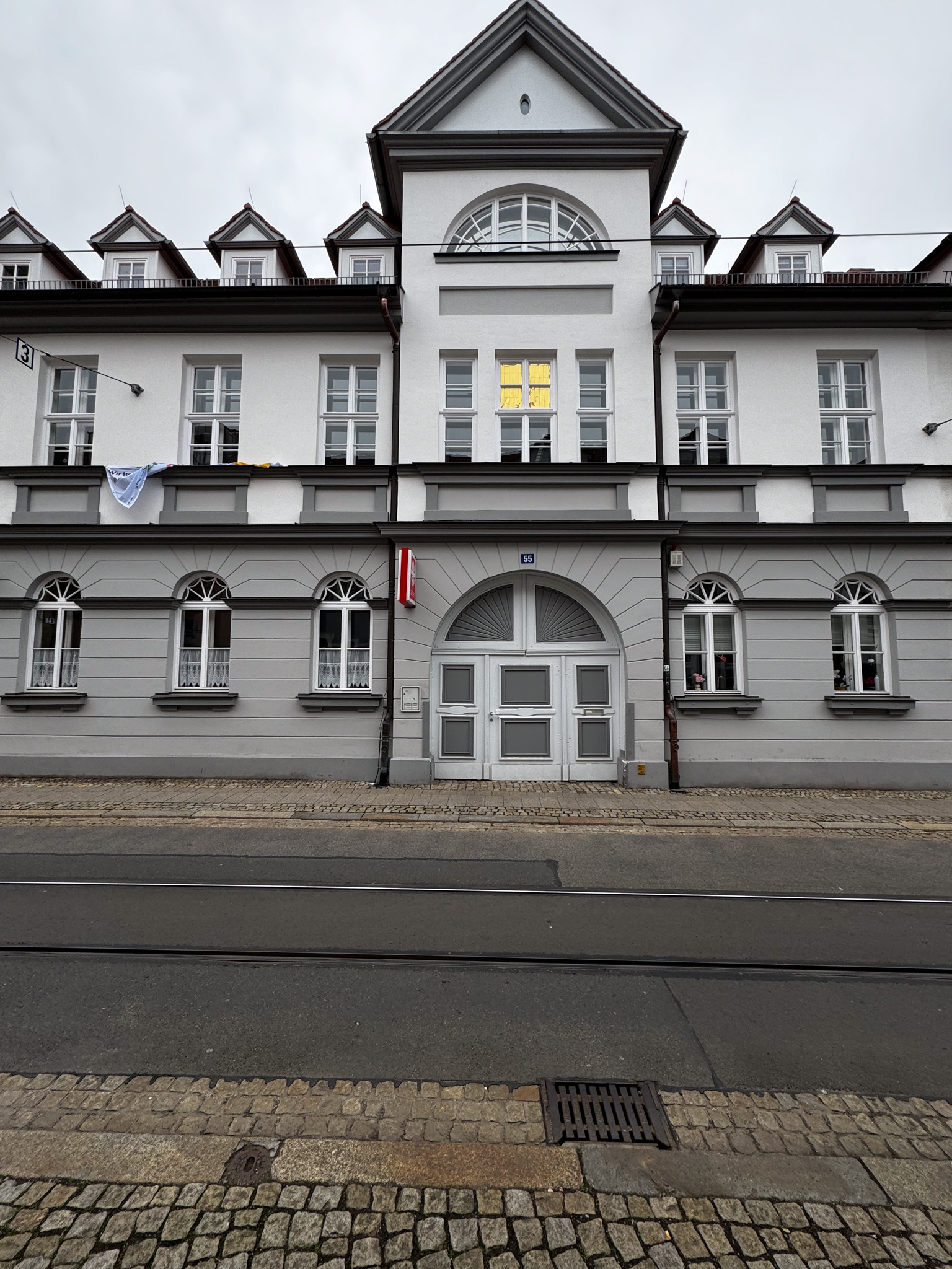 Mehrfamilienhaus mit grau-weiß gestrichener Fassade und Rundbogenportal