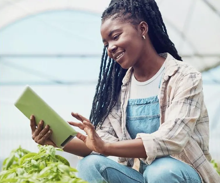 An entrepreneur checking her business on a tablet in a greenhouse