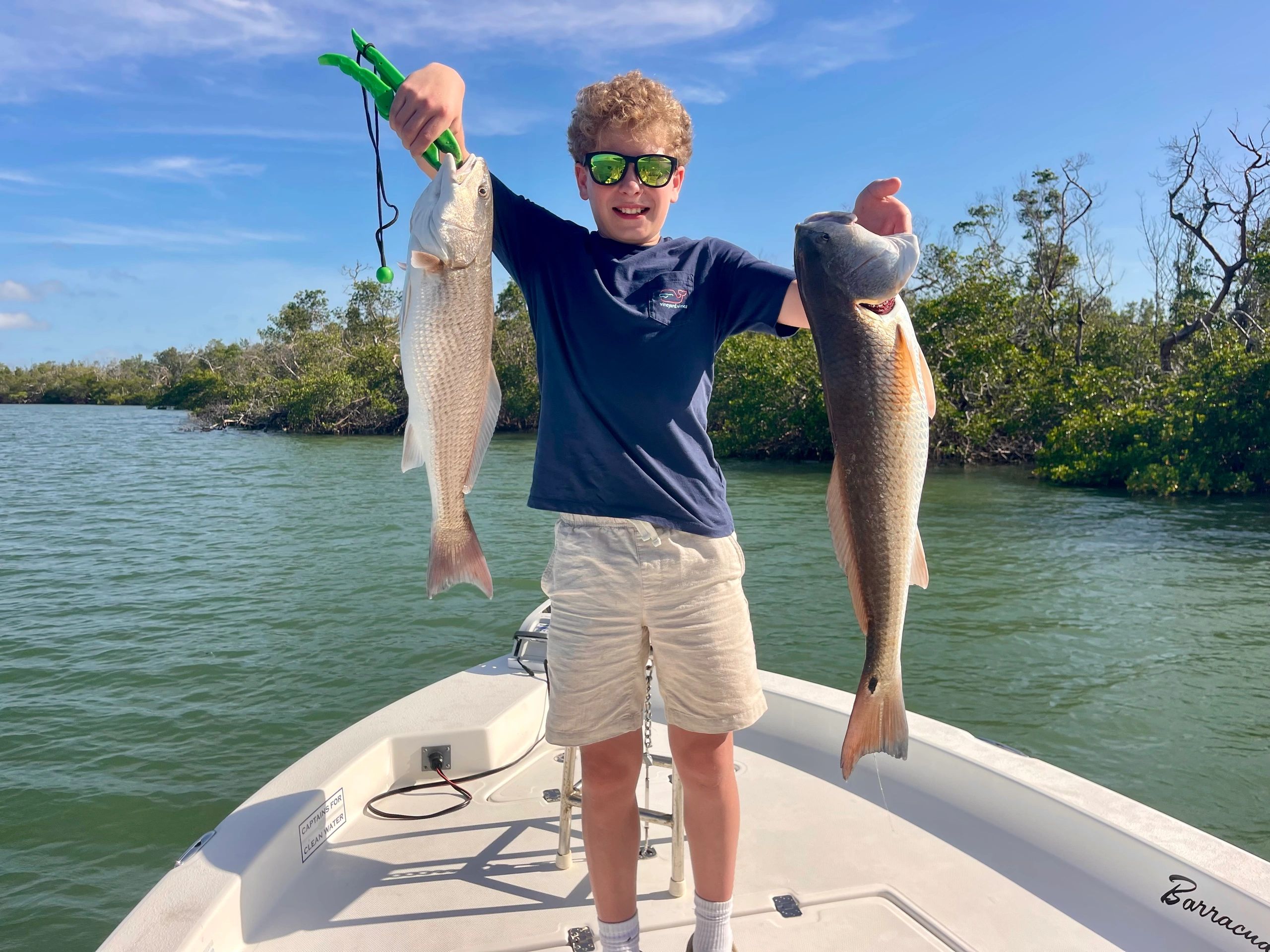 Young angler holding two redfish aboard the Un-Reel on a Charlotte Harbor fishing charter
