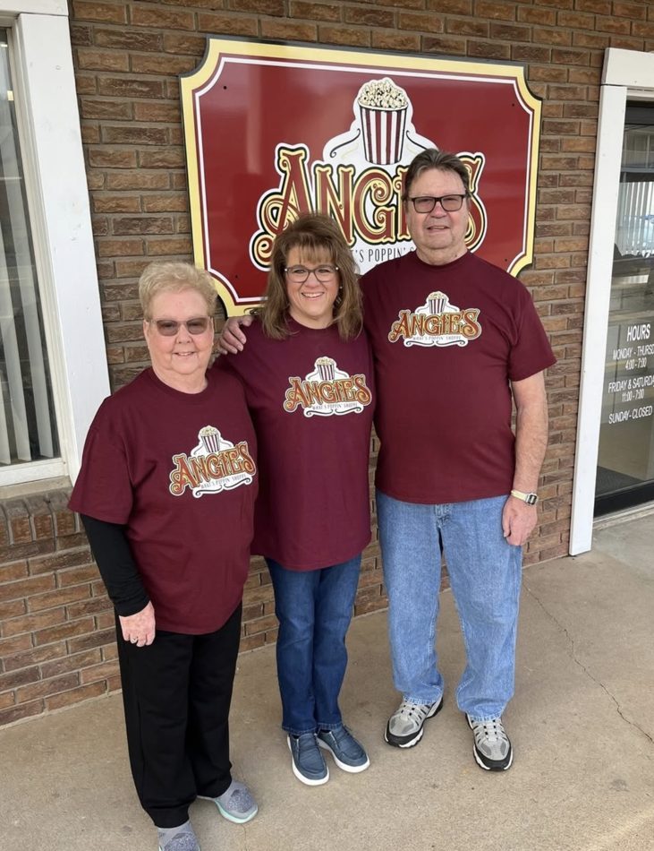 Three people in maroon Angie’s shirts outside the shop