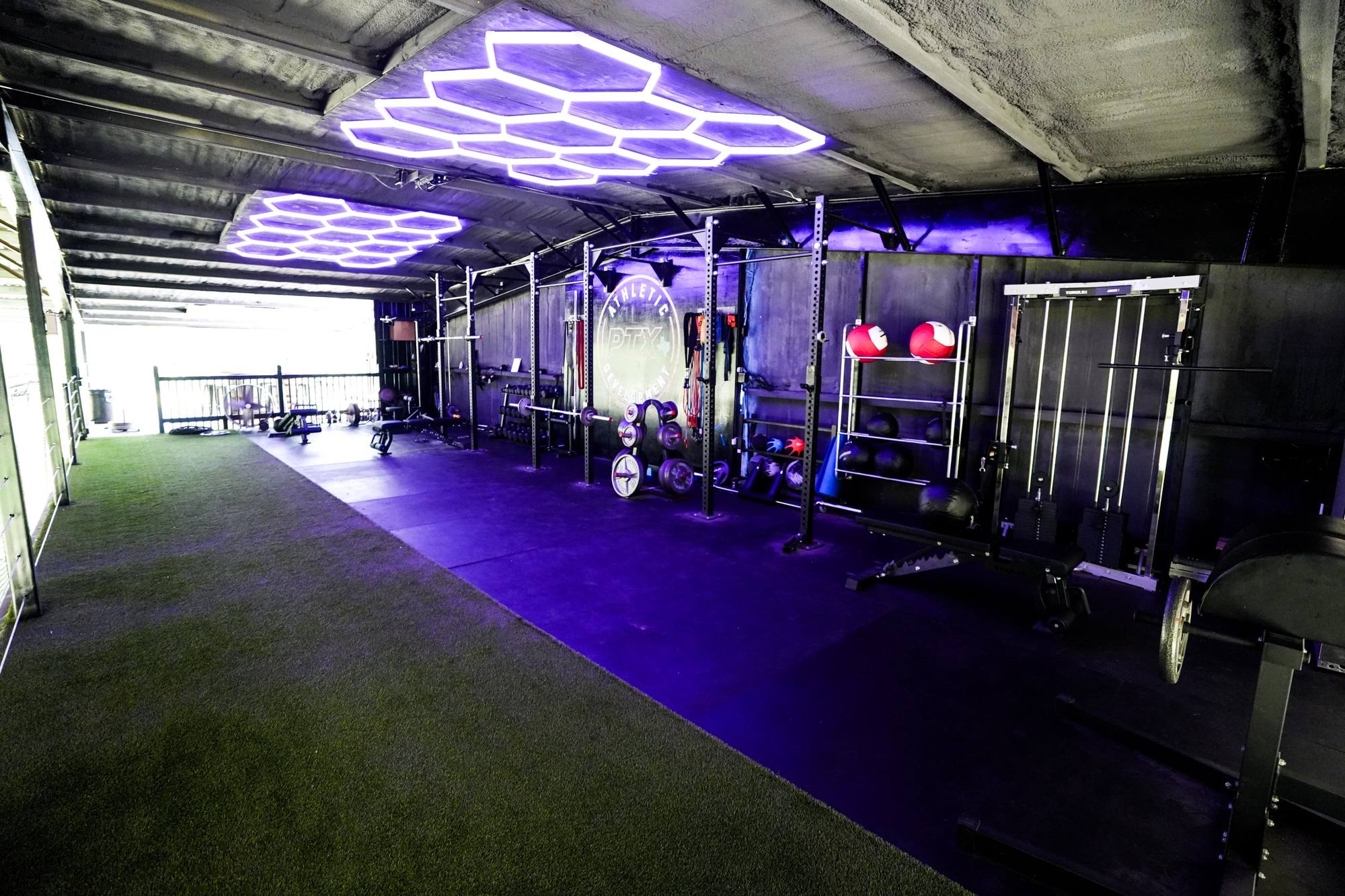 PTX Athletic Development training room with racks, turf and lights