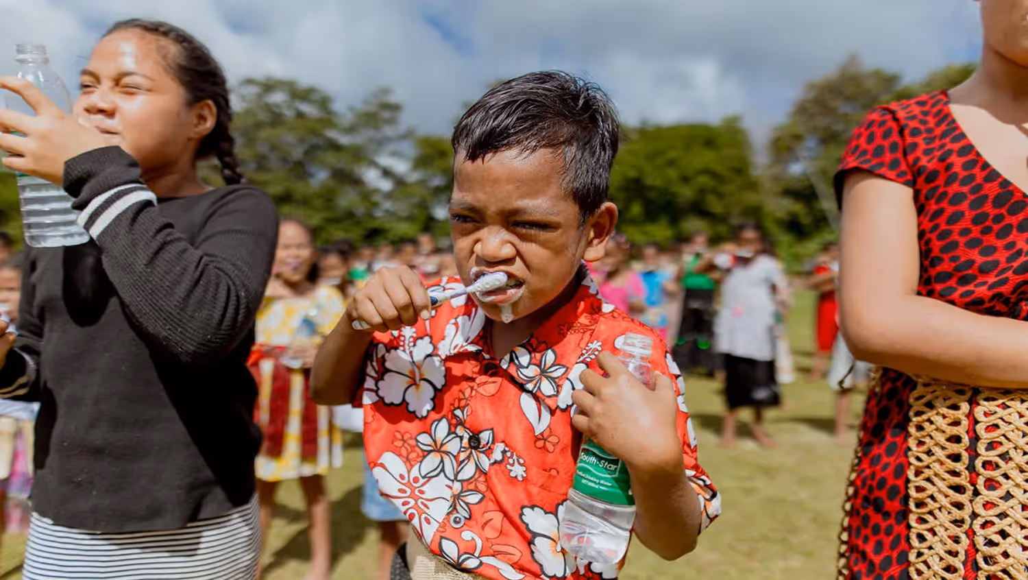 Young people brushing their teeth outdoors during a group oral health activity