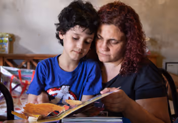 Woman and young boy reading a picture book together at a table