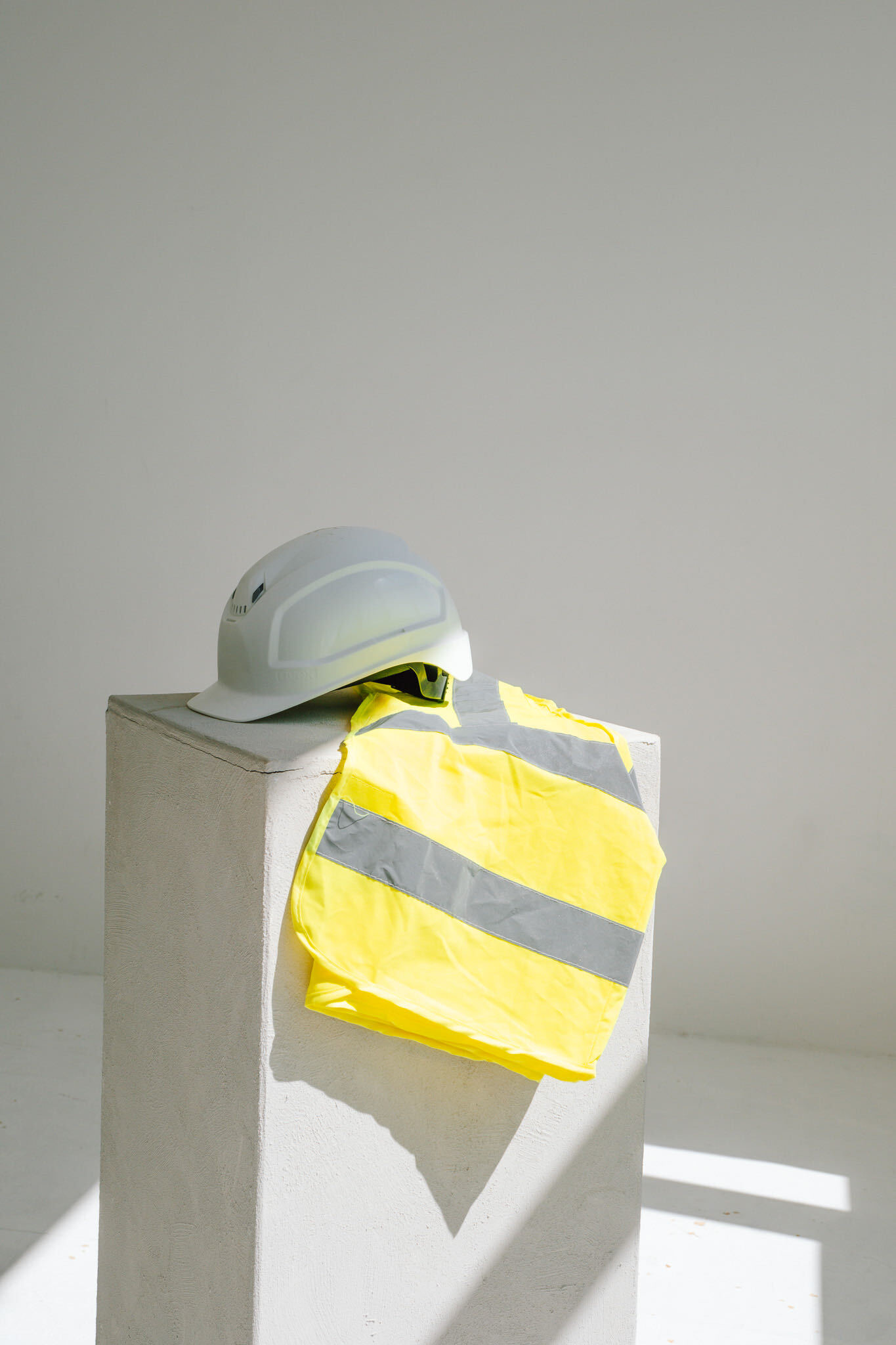 Schutzhelm und Warnweste auf einem Betonsockel