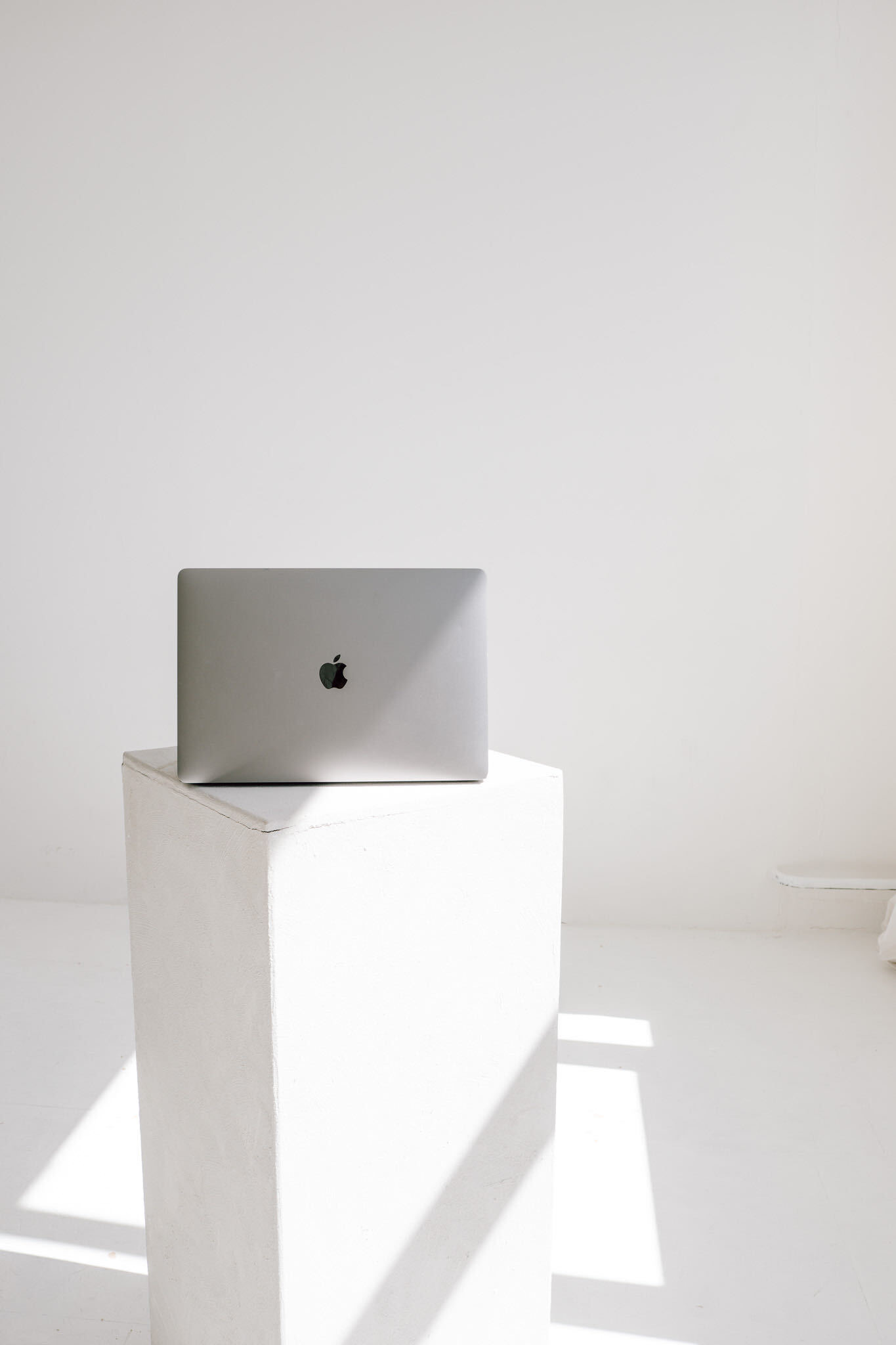 Laptop auf einem hellen Sockel im Sonnenlicht