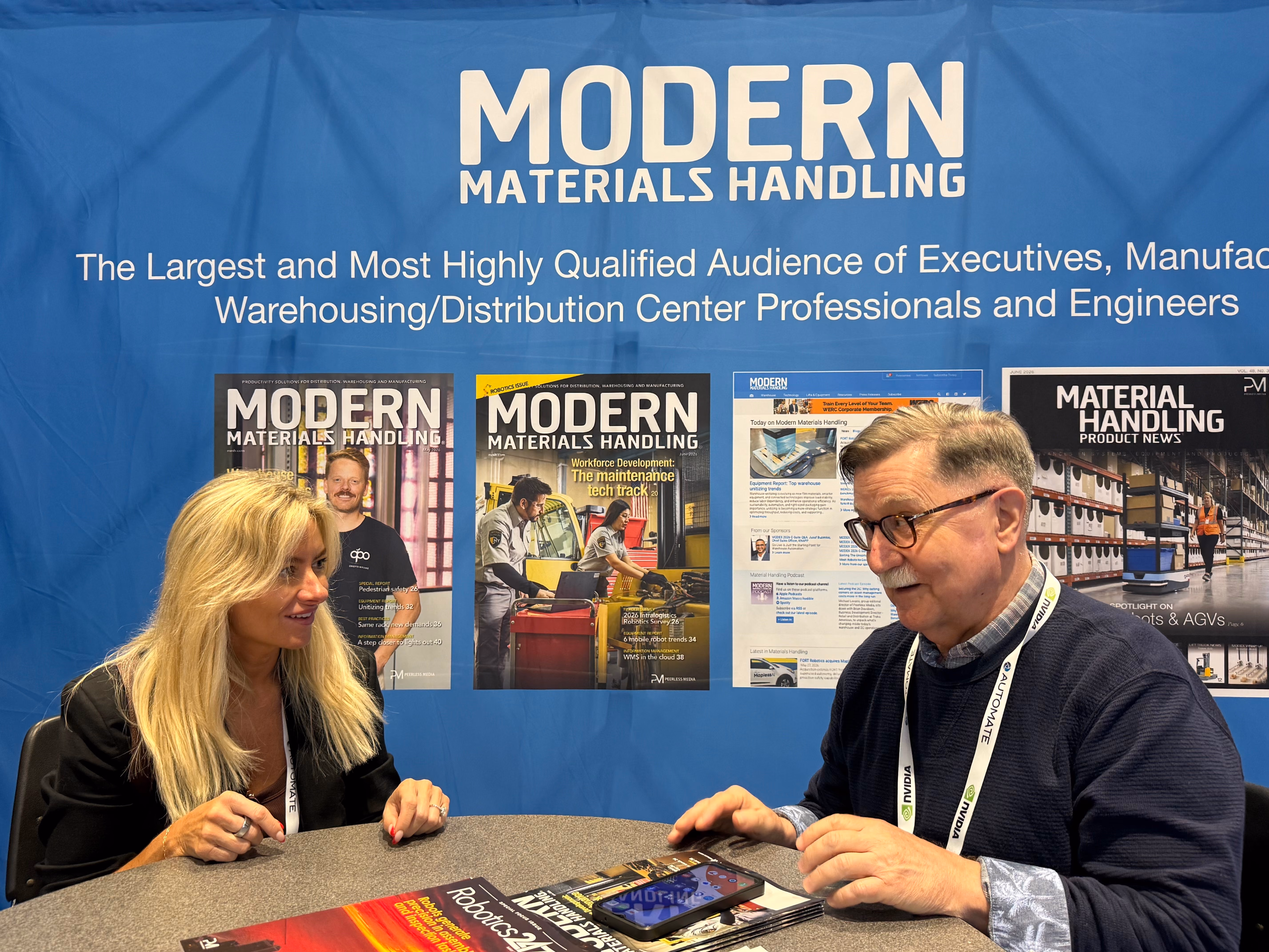 Mandy talking to a guest sitting at a table with Modern Materials Handling magazines.