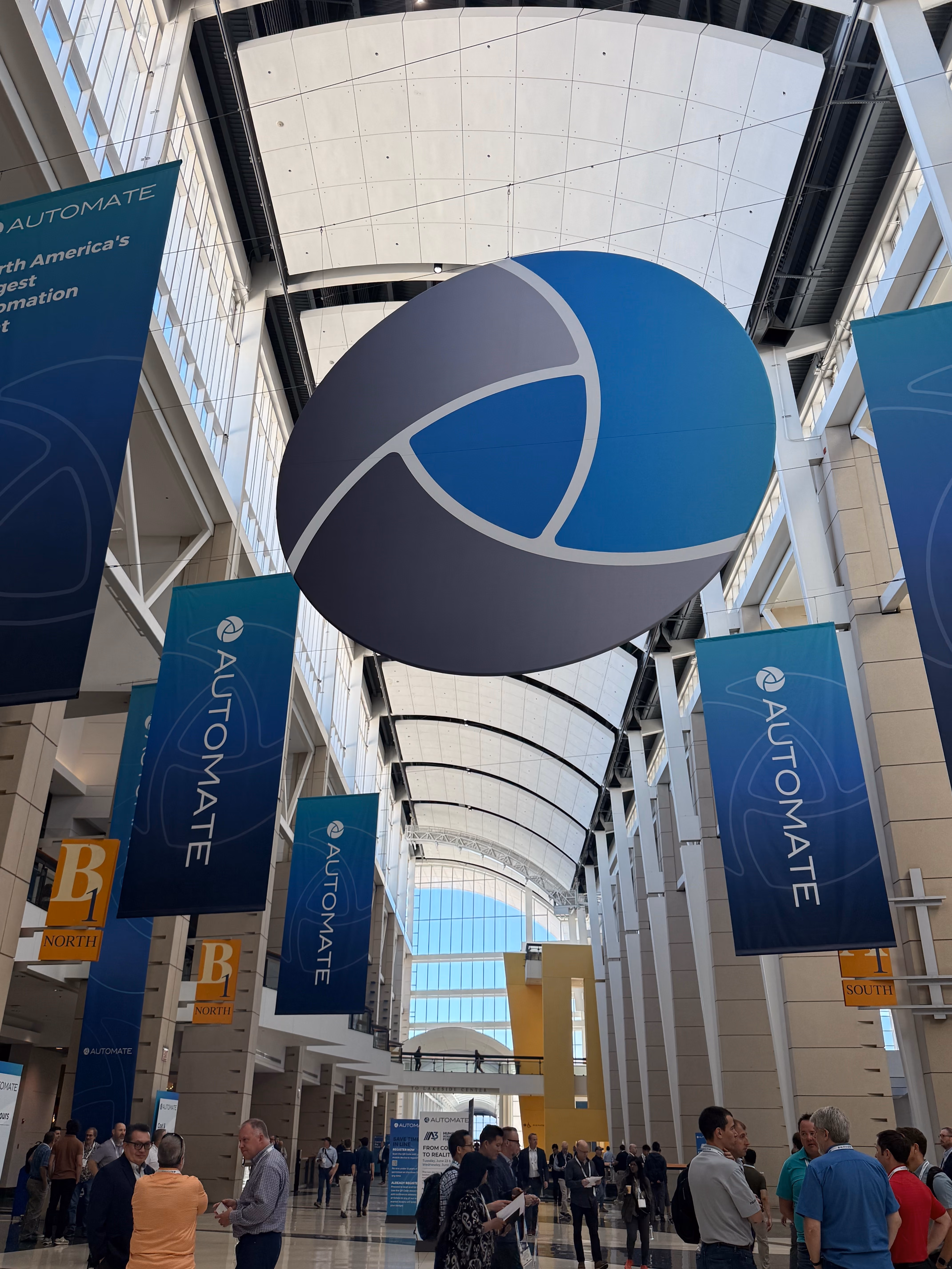 Crowded convention center hall with large hanging banners with the Automate logo.
