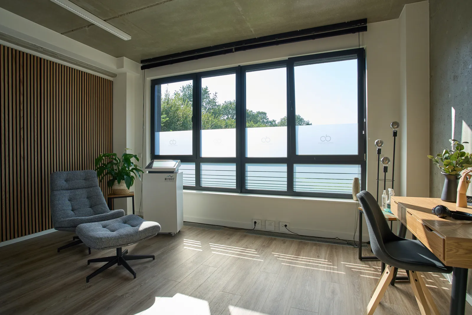 Heller Praxisraum mit Sitzecke und Schreibtisch