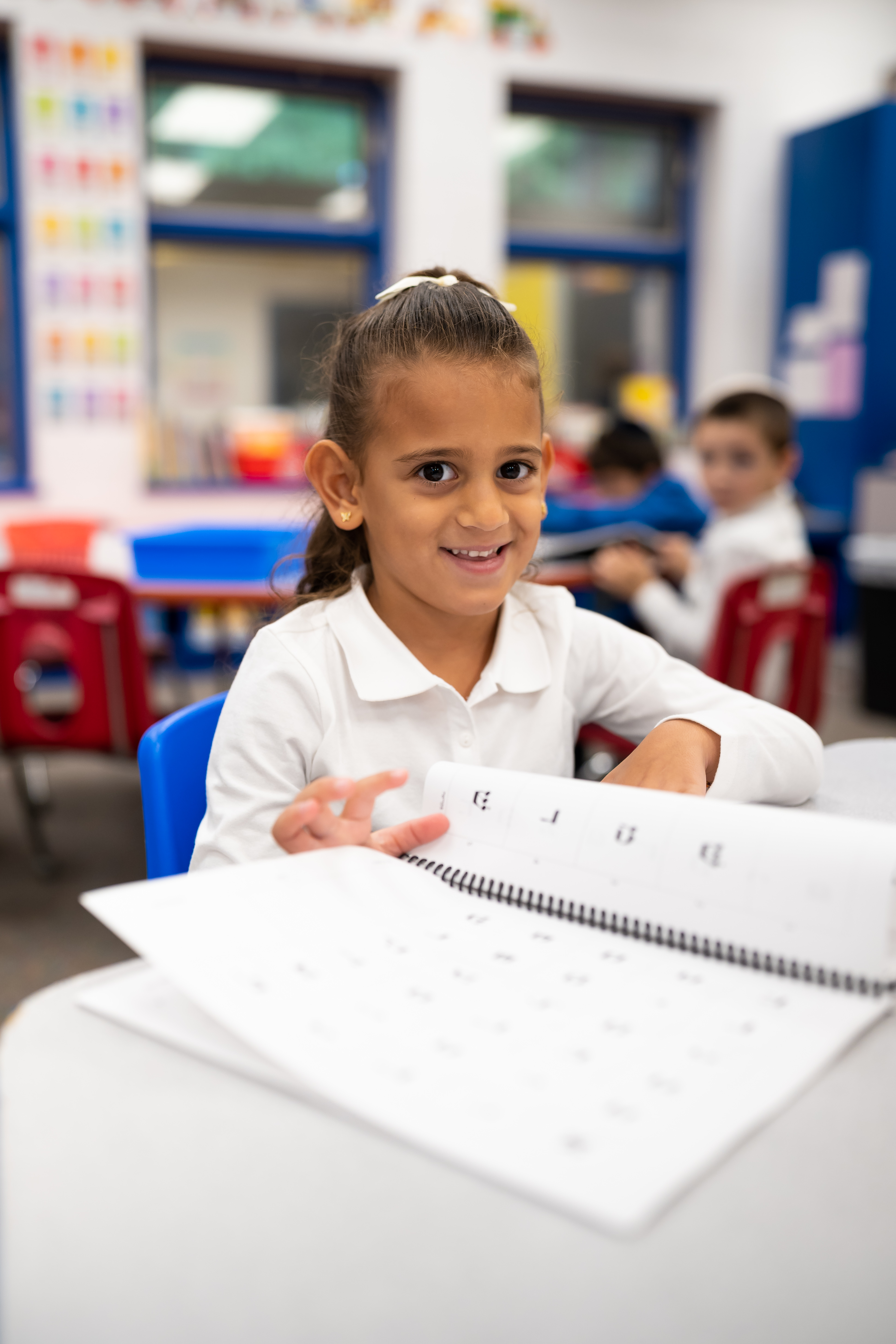 Smiling Kindergarten student with her workbook