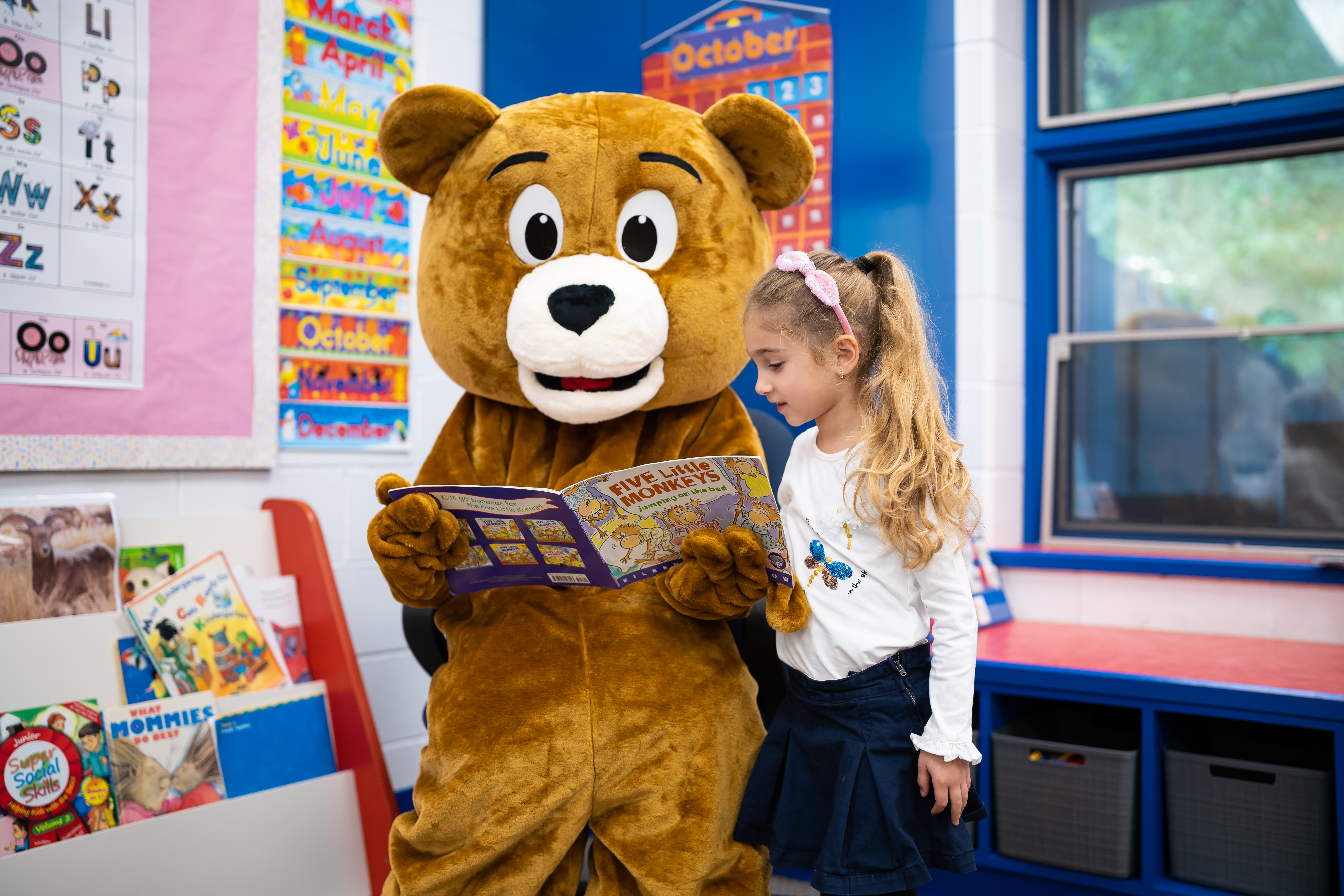 Kobi the bear reading a book with a student