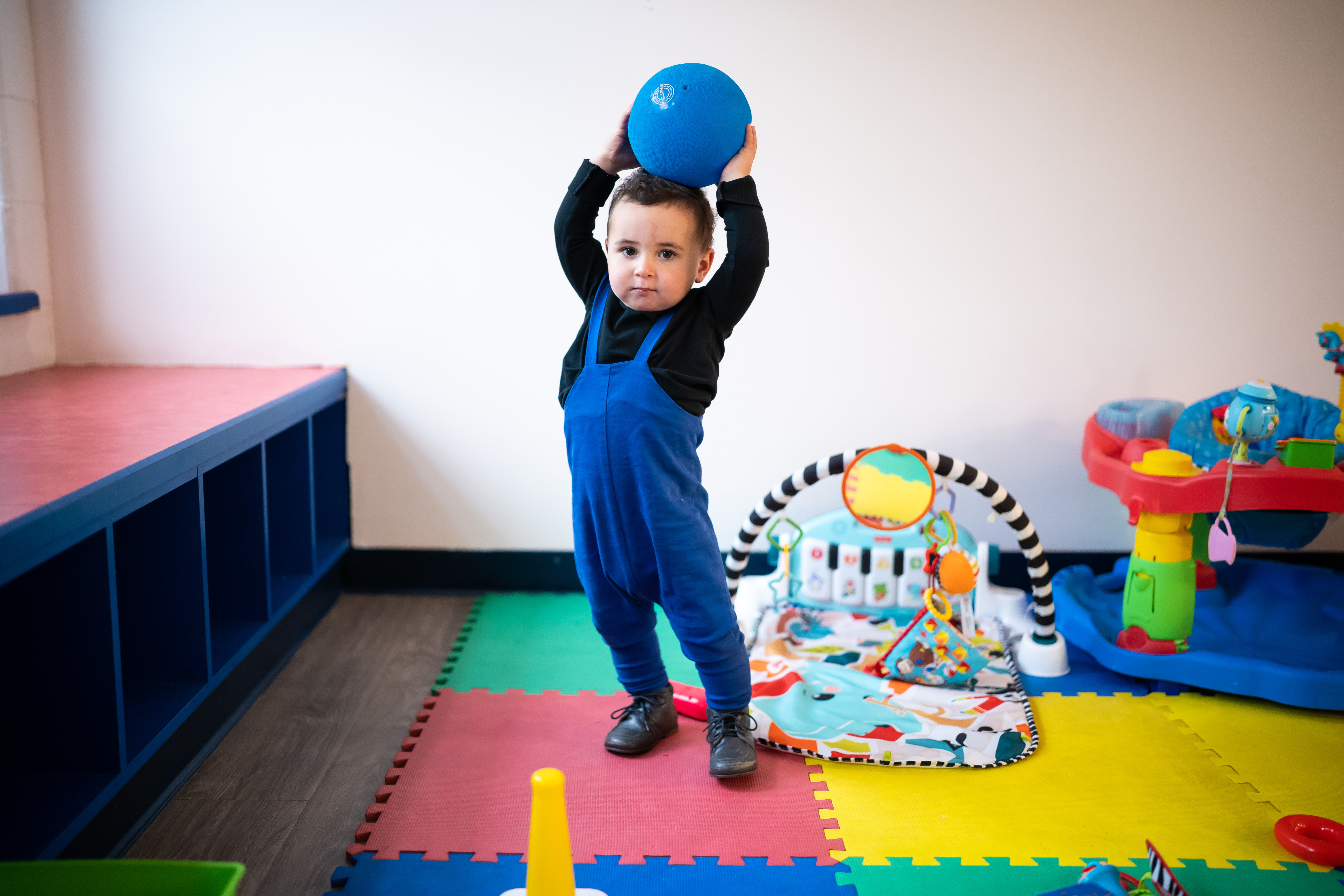 Toddler lifting a big blue ball