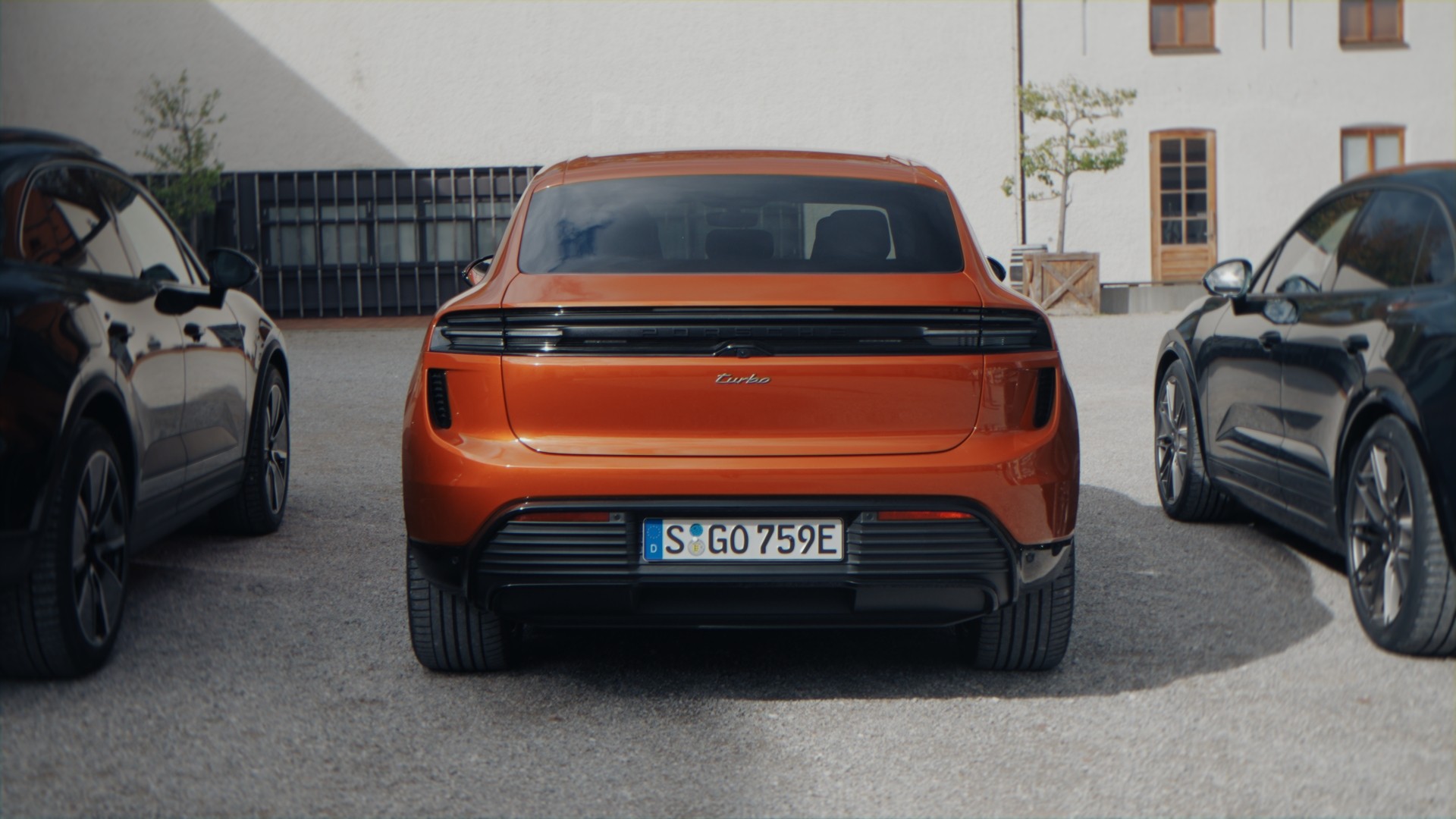 Oranger Porsche Macan von hinten zwischen anderen Porsche-Modellen