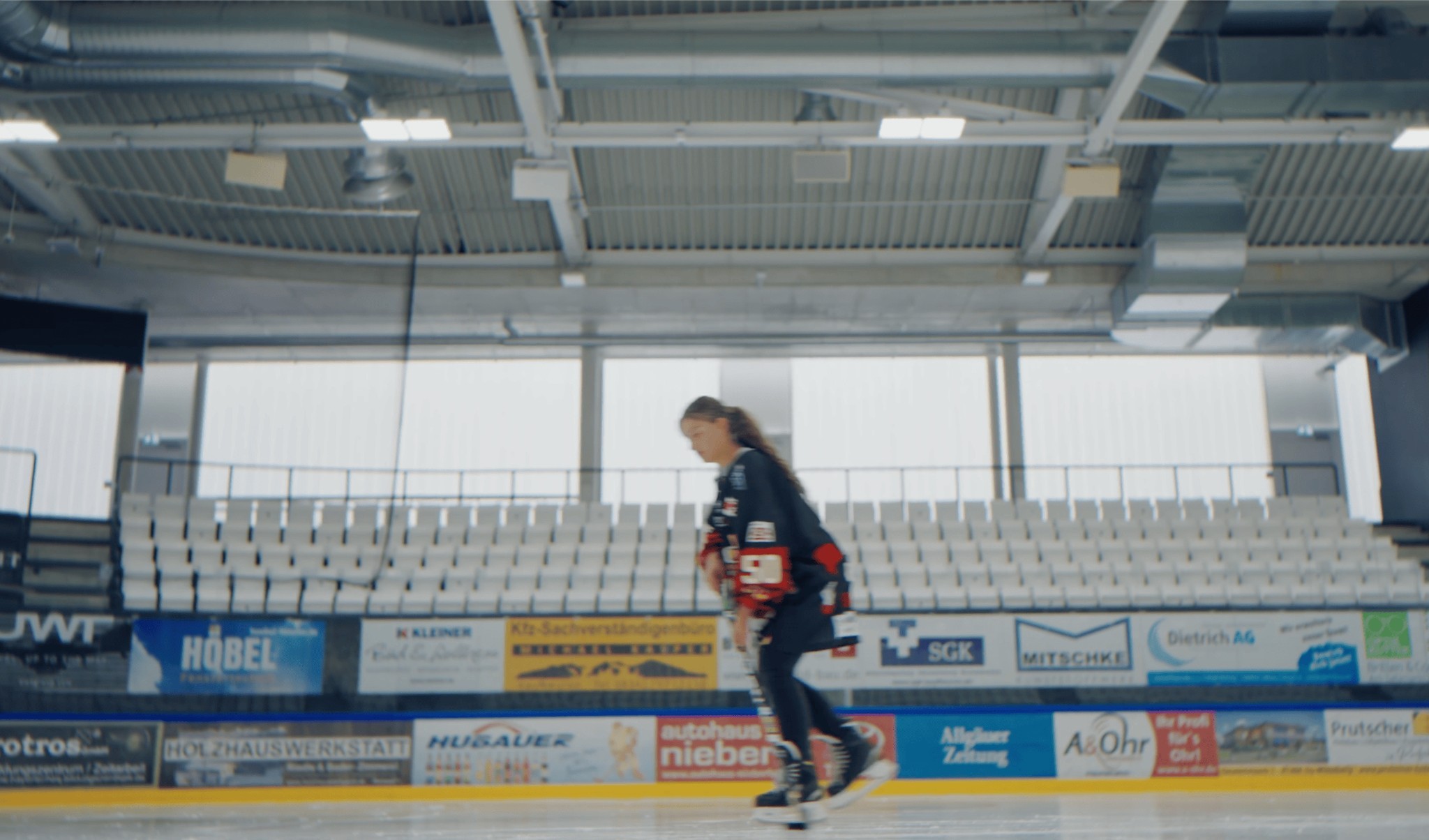 Eishockeyspieler auf dem Eis vor Banden mit Höbel-Werbung, Imagefilm Höbel