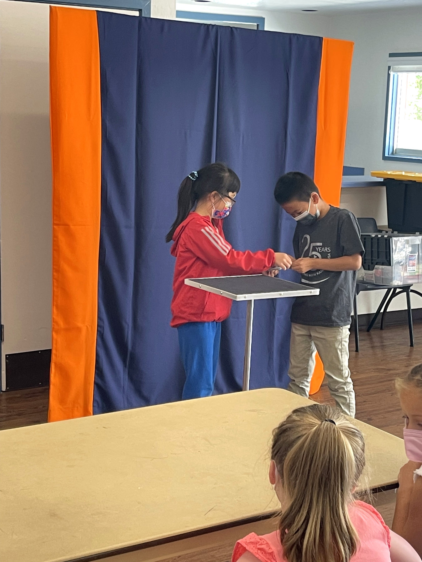 Two young students performing a magic trick together for classmates