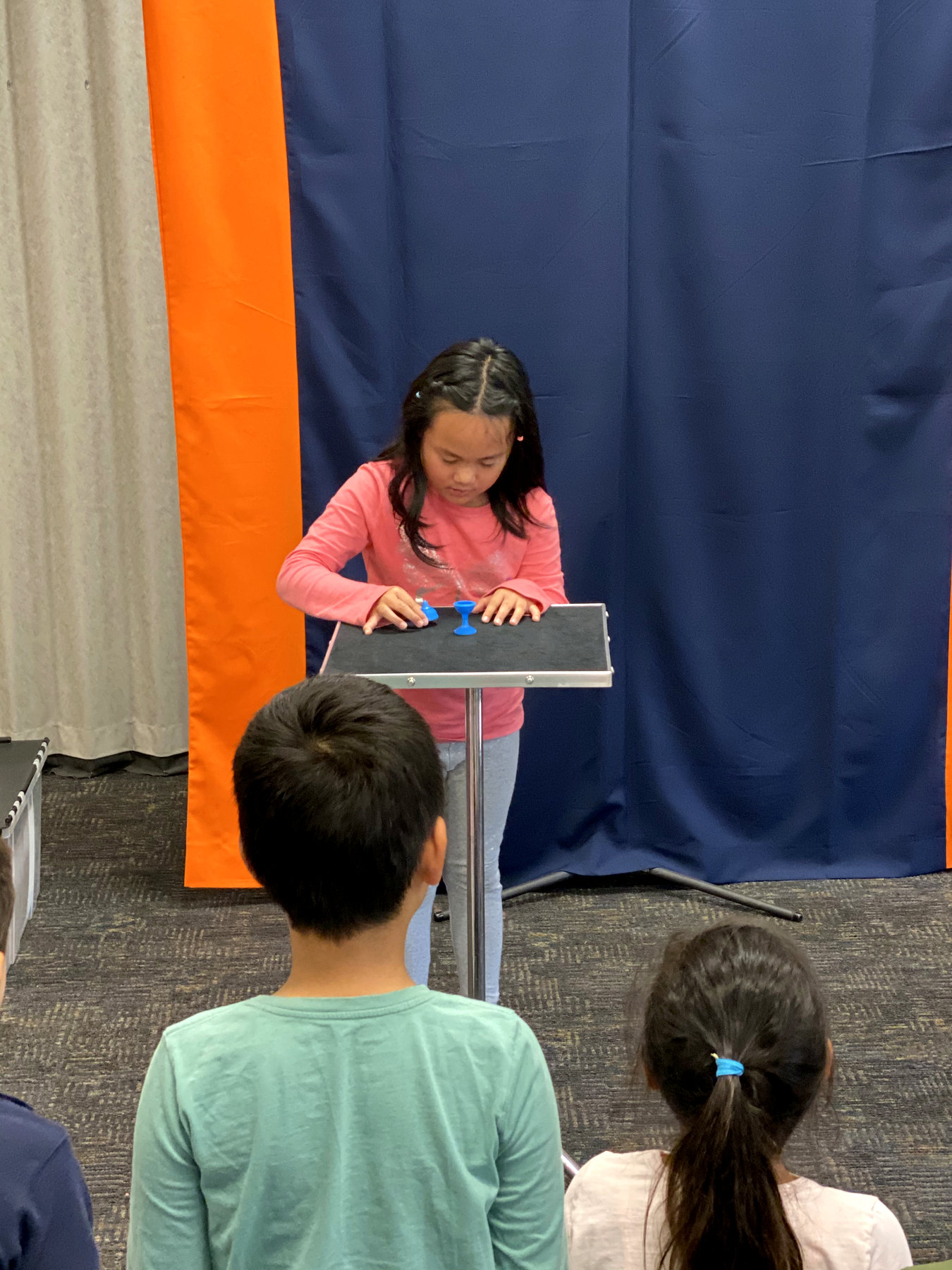 Young magician performing a trick as classmates watch