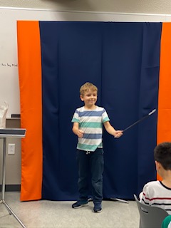 Young magician presenting a wand trick for classmates