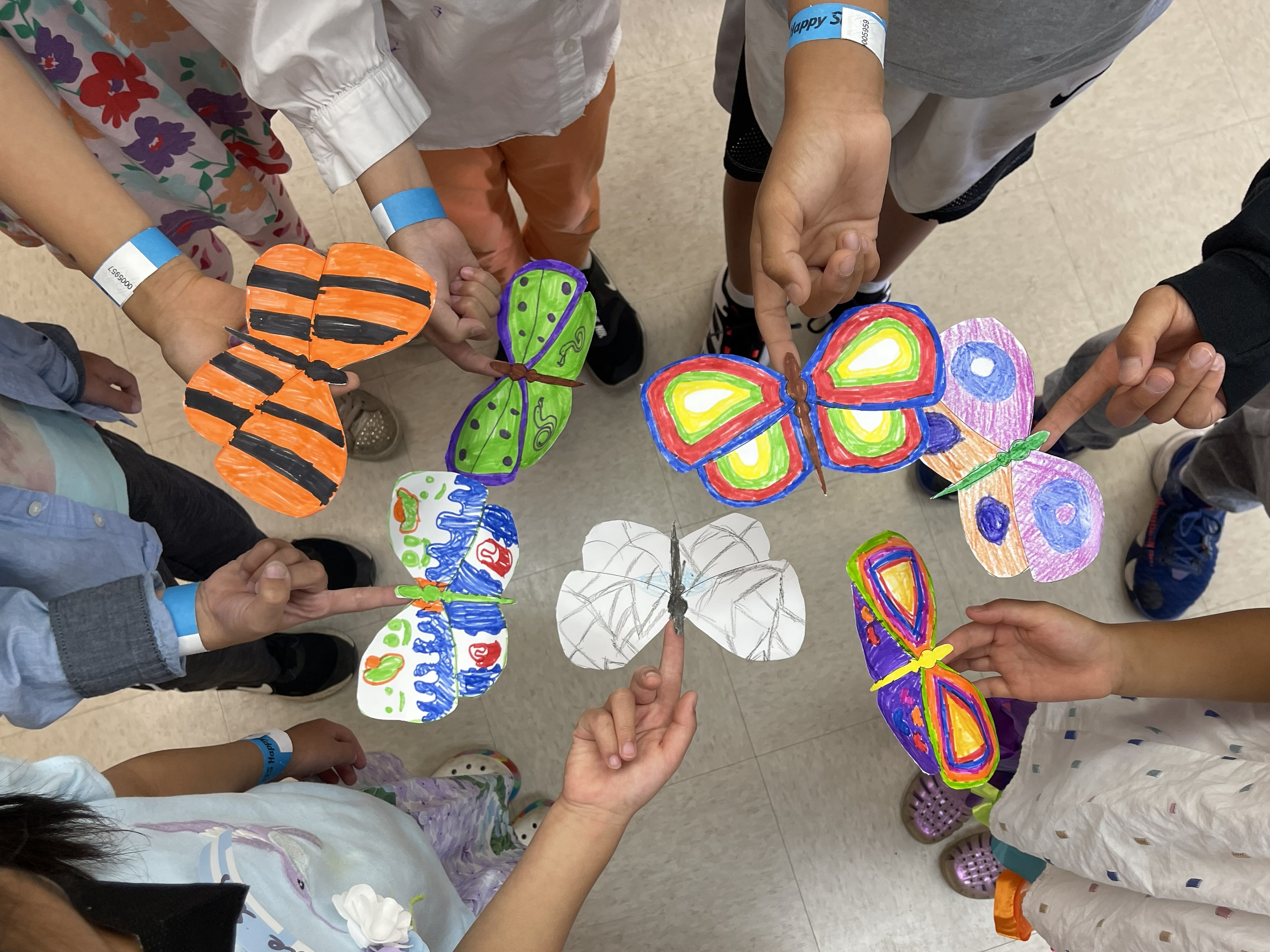 Children proudly sharing colorful butterfly creations from a magic class activity