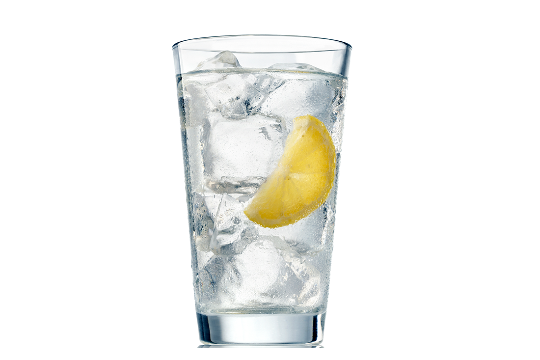 Clear glass filled with ice cubes, sparkling water, and a lemon wedge.